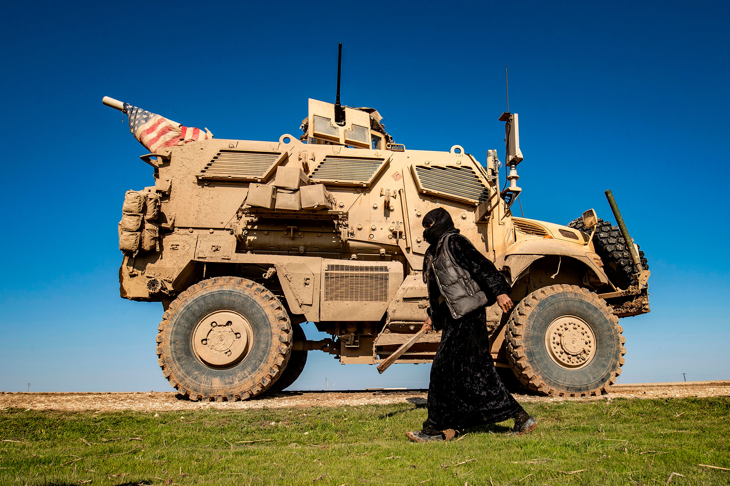 A woman passes a U.S. military vehicle in northeast Syria on Jan. 22