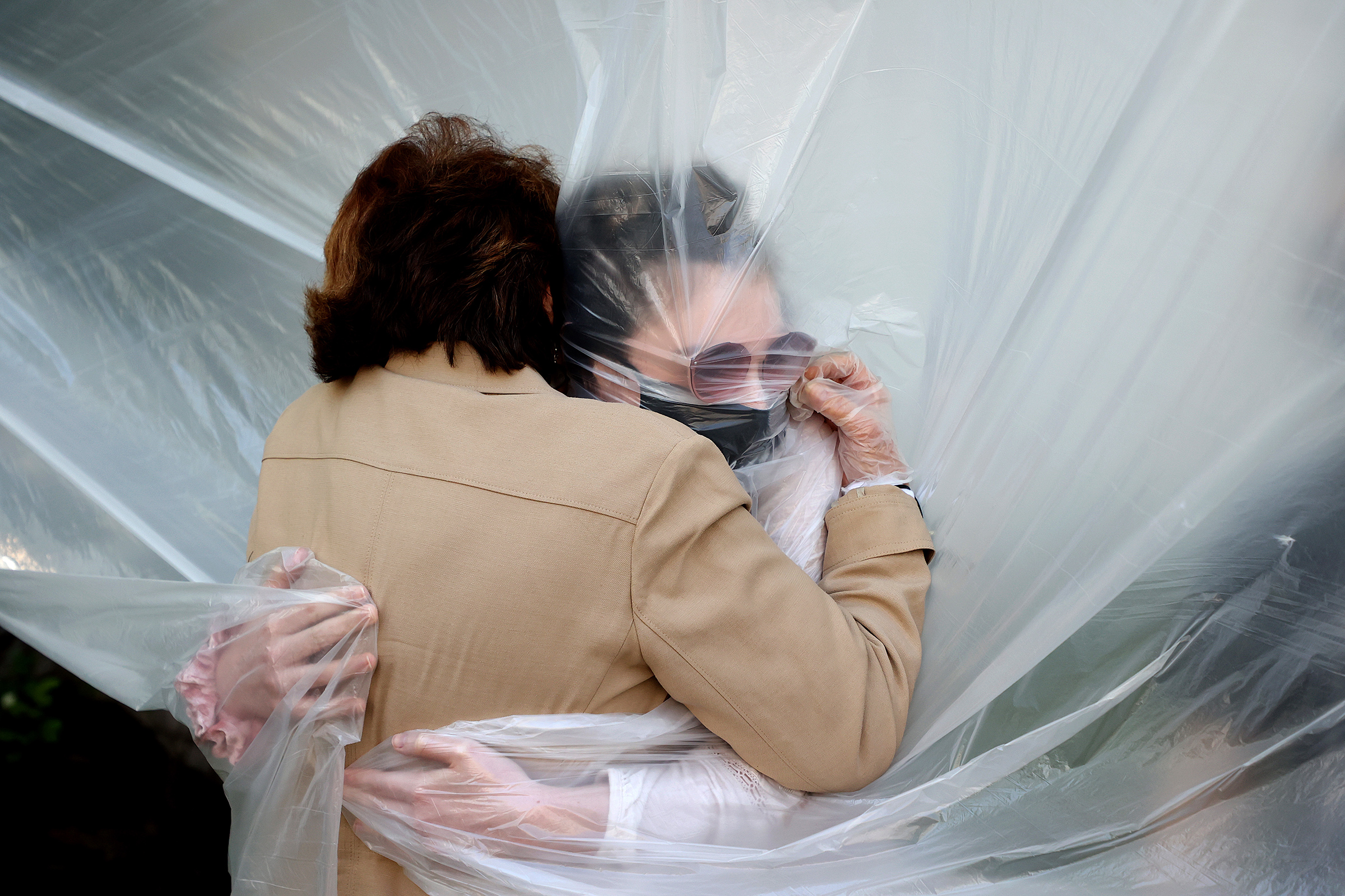 Olivia Grant, right, hugs her grandmother, Mary Grace Sileo, through a plastic drop cloth hung up on a clothesline in a backyard in Wantagh, N.Y., on May 24. It was the first time they have had contact of any kind since the pandemic lockdown began.
