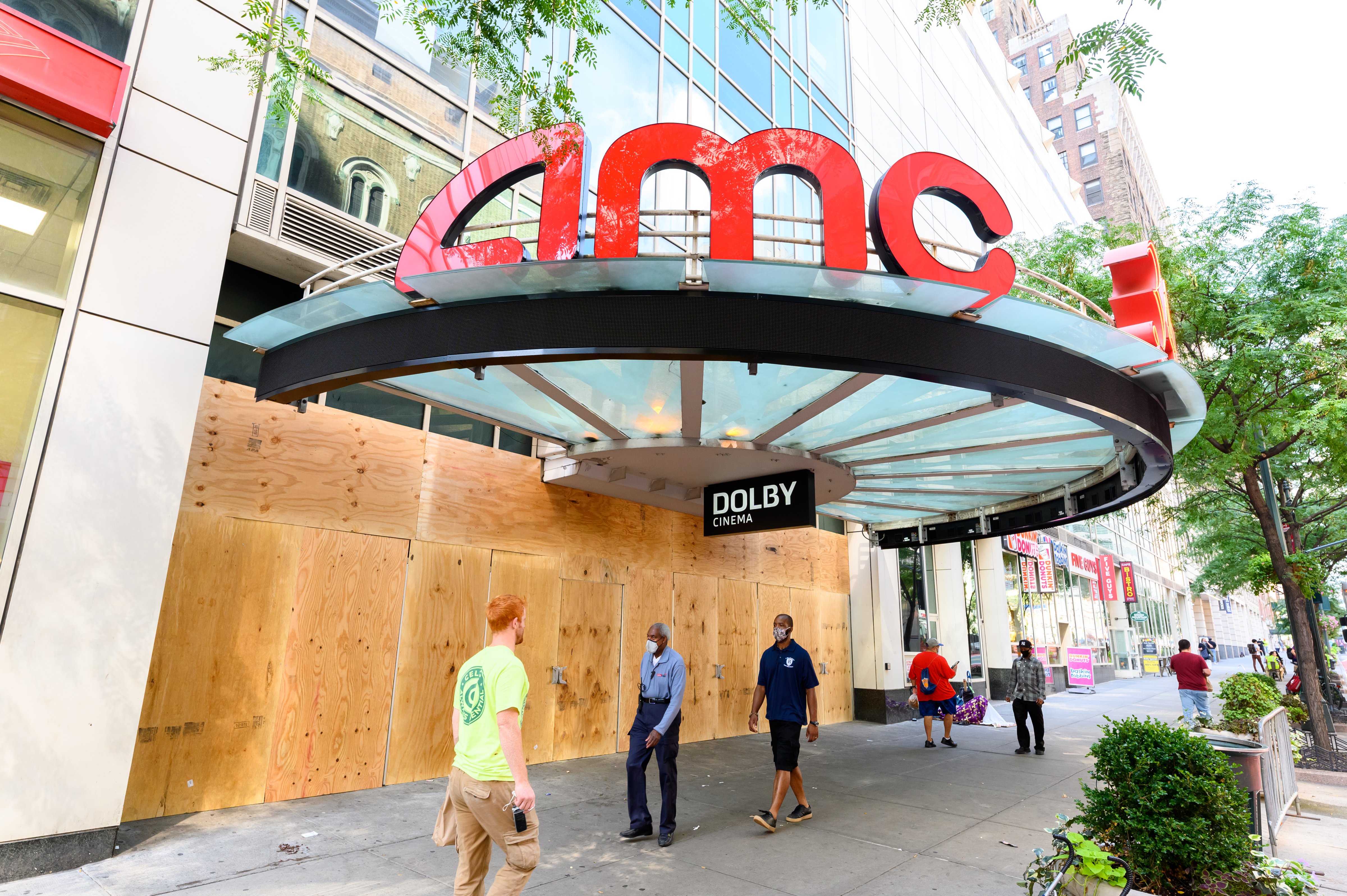 People walk outside the newly boarded AMC 34th Street 14 movie theater (Noam Galai—Getty Images)