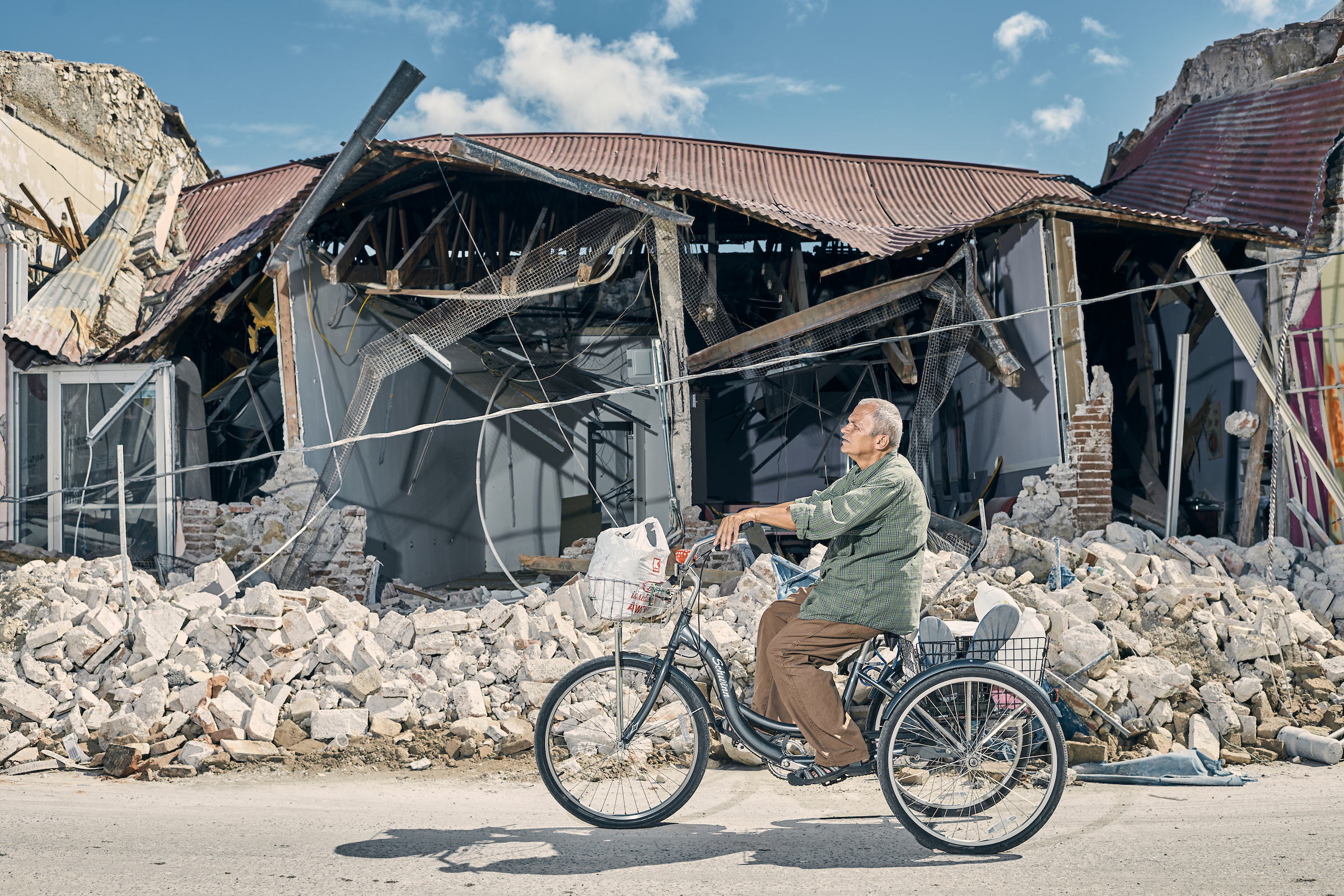 A man rides his tricycle in front of destroyed buildings in the town center of Guanica, Puerto Rico, on Jan. 8.