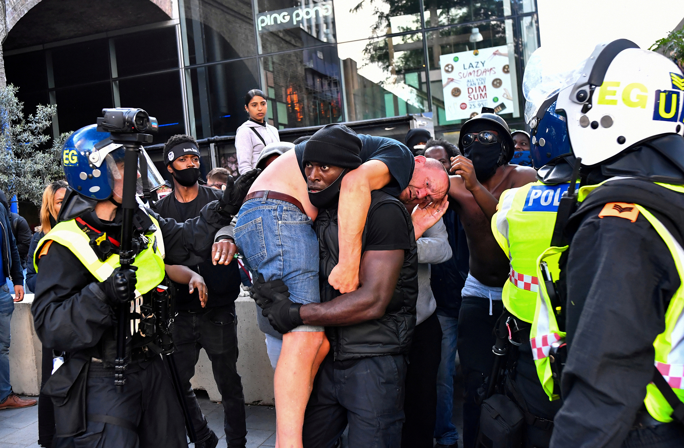 During a Black Lives Matter demonstration in London on June 13, protester Patrick Hutchinson carries an injured counter-protester to safety near Waterloo Station. (Dylan Martinez—Reuters)