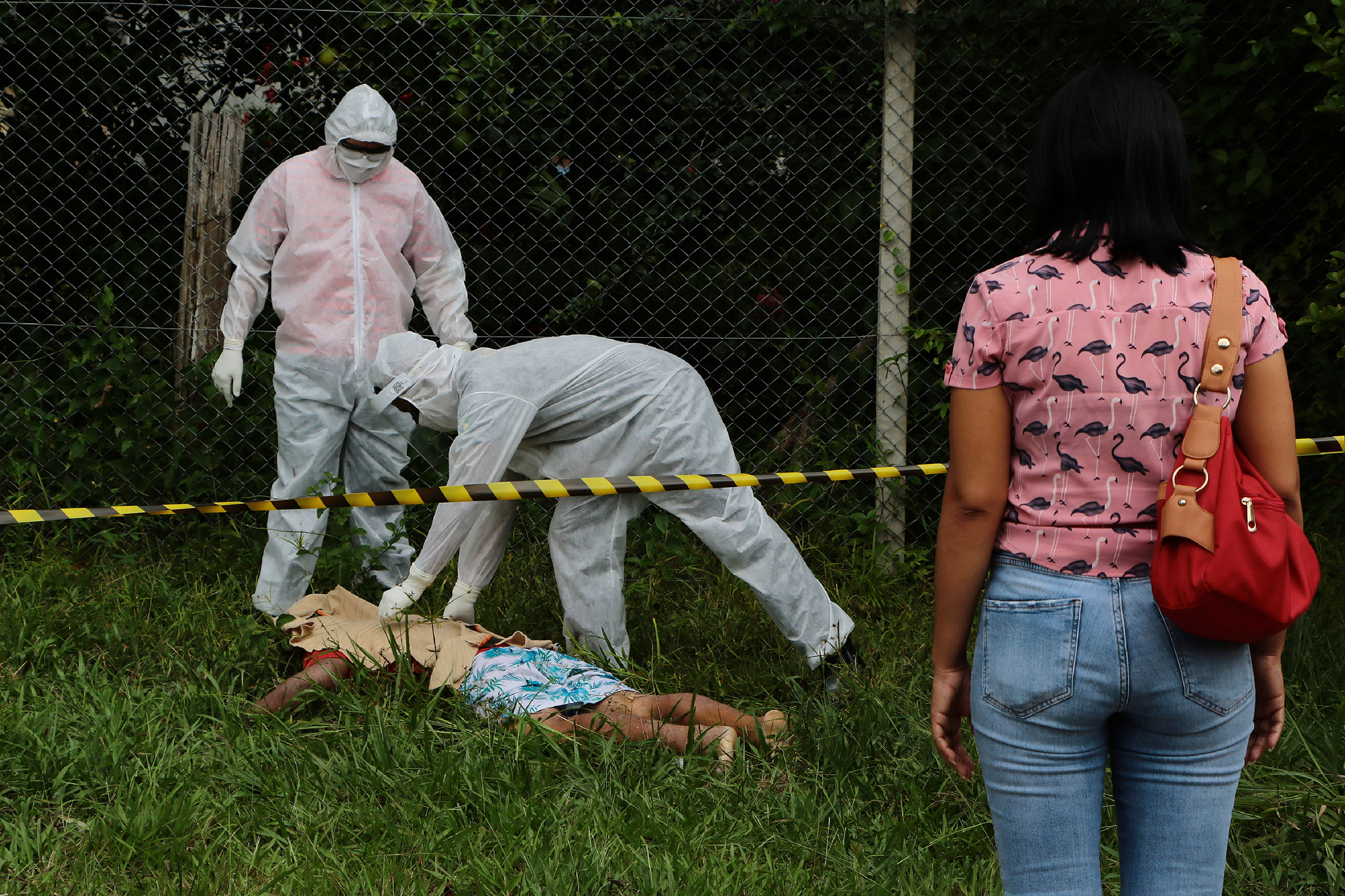 Government funeral workers cover the body of Arlen Laranjeira Bezerra, 39, near the Delphina Rinaldi Abdel Aziz Hospital in Manaus, in the Brazilian state of Amazonas, on May 5. Bezerra had been admitted to the hospital to undergo treatment for COVID-19. After escaping from the hospital at dawn, his body was found by family members approximately 650 feet (200 meters) away. (Edmar Barros—AP)