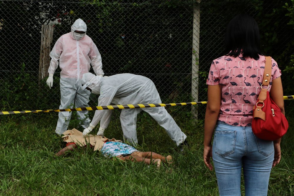 Government funeral workers cover the body of Arlen Laranjeira Bezerra, 39, near the Delphina Rinaldi Abdel Aziz Hospital in Manaus, in the Brazilian state of Amazonas, on May 5. Bezerra had been admitted to the hospital to undergo treatment for COVID-19. After escaping from the hospital at dawn, his body was found by family members approximately 650 feet (200 meters) away.