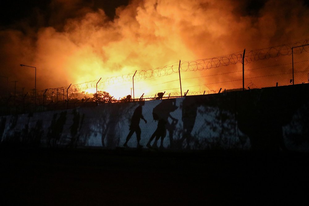 Shadows of refugees and migrants carrying their belongings are seen as they flee from a fire at the Moria camp on the Greek island of Lesbos on Sept. 9.
