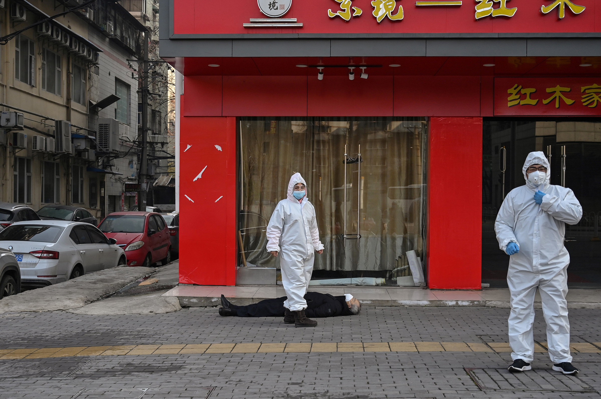 Officials in protective suits near an elderly man who collapsed and died near a hospital in Wuhan, China, on Jan. 30. (Hector Retamal—AFP/Getty Images)
