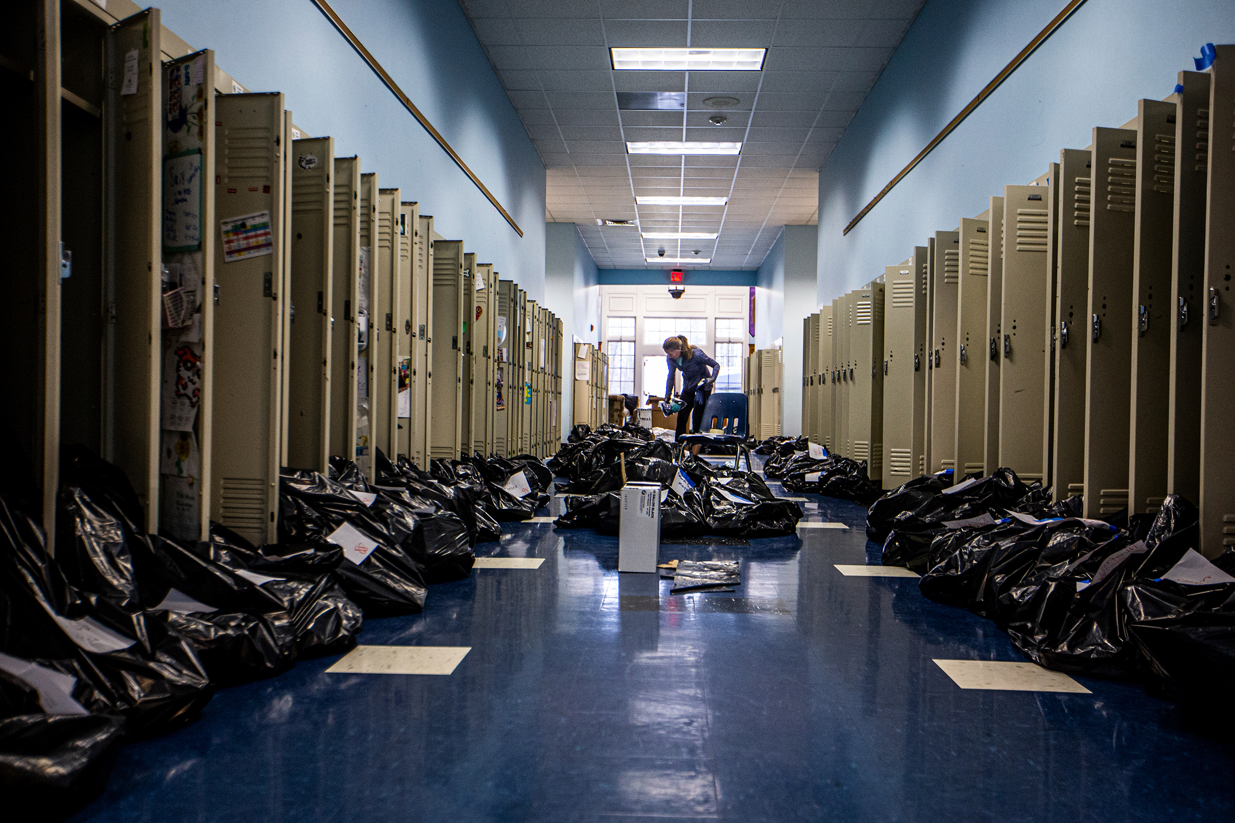 Kelen Walker packs students' locker contents into black trash bags as they clean and sanitize the school while students take online classes from home at Canterbury School in Greensboro, N.C., on March 17. (Khadejeh Nikouyeh—News &amp; Record/AP)