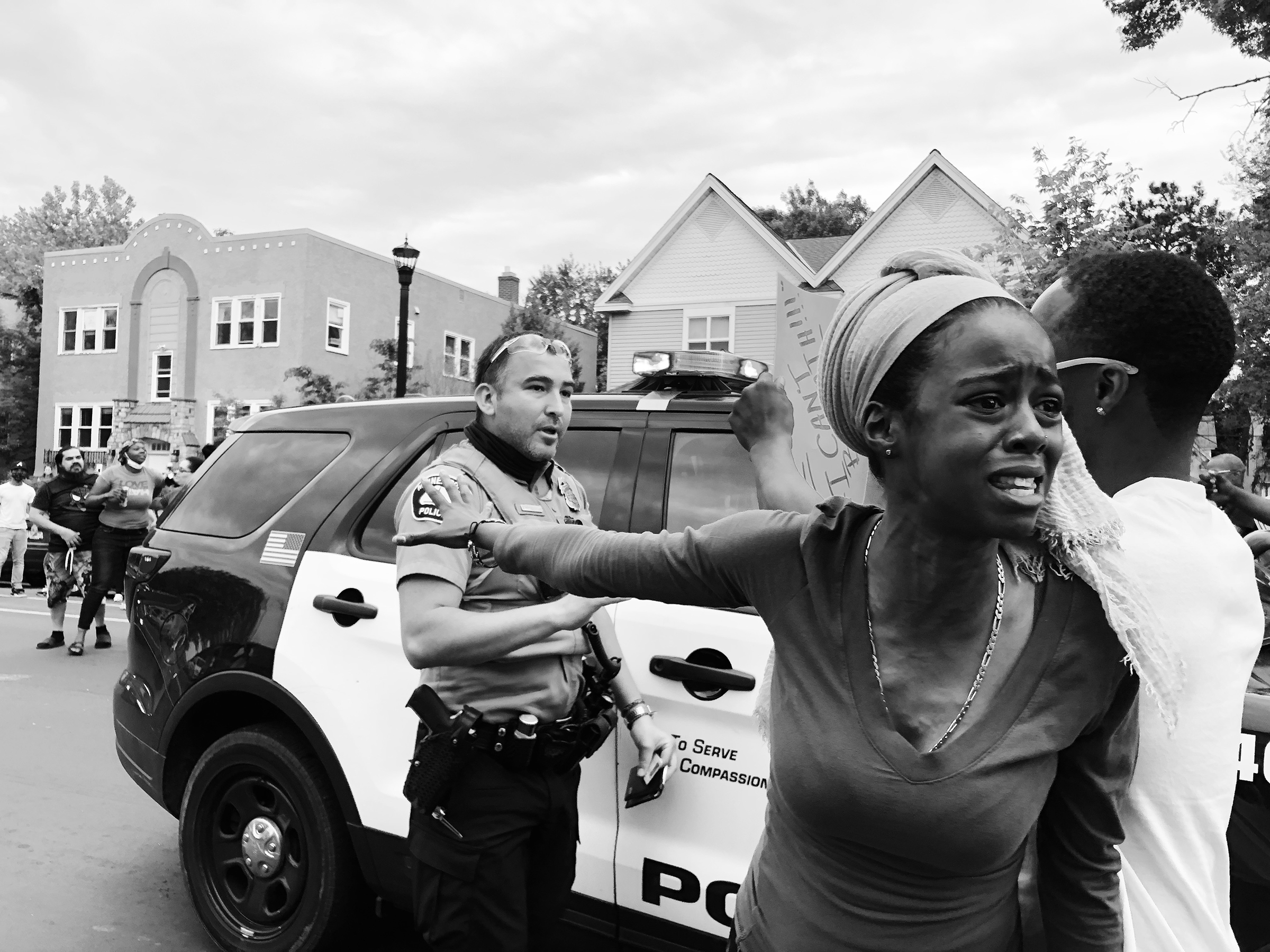 A woman outraged by the killing of George Floyd speaks to a crowd and blocks a police officer's vehicle with a group of protesters in Minneapolis on May 27, 2020.