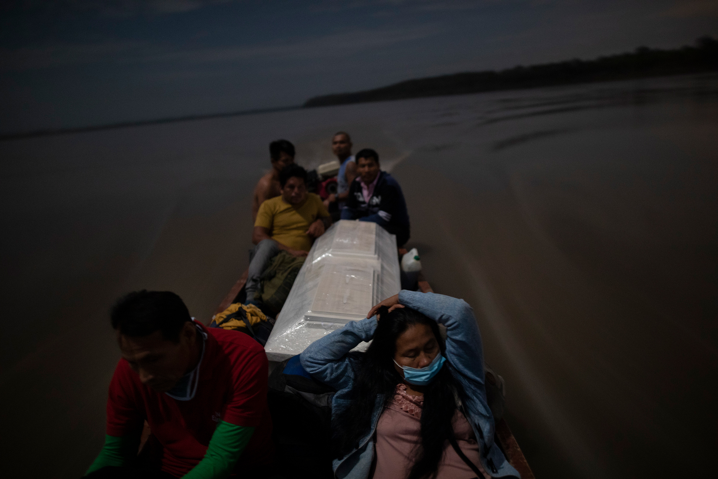 Relatives accompany the coffin of Jose Barbaran, who was believed to have died from coronavirus complications, as they travel by boat on Peru's Ucayali River on Sept. 29. Despite the risk, family members decided to travel by night to Barbaran's hometown of Palestina, a four-hour journey. (Rodrigo Abd—AP)