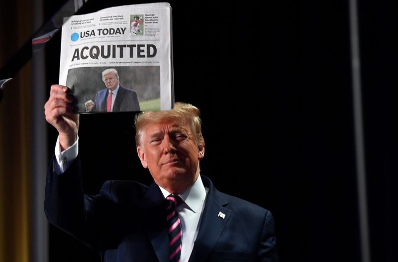 U.S. President Donald Trump holds up the front page of USA Today that displays a headline  Acquitted  as he arrives to speak at the 68th annual National Prayer Breakfast on February 6, 2020.