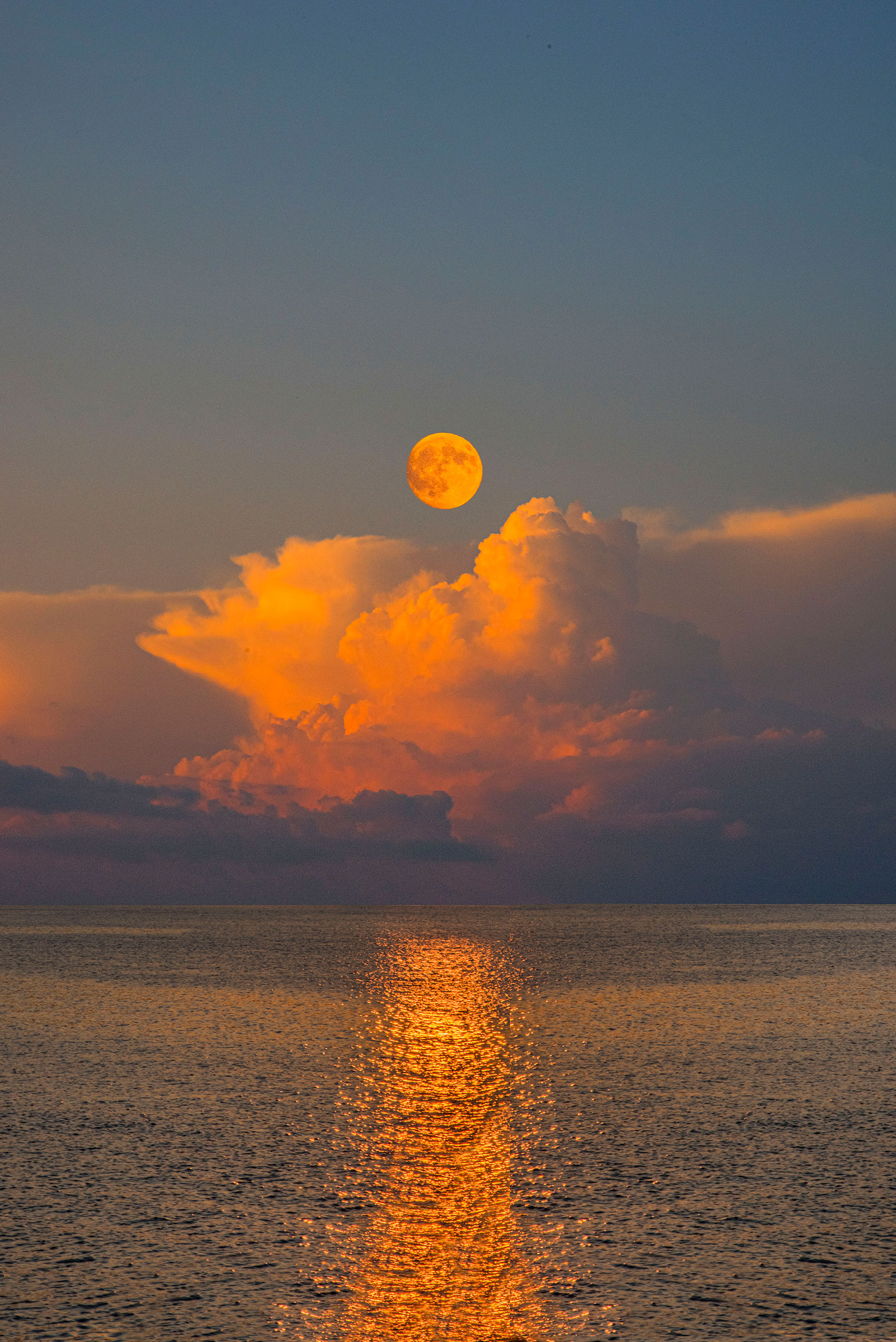 a photo-illustration of the moon acting as sunlight over the ocean