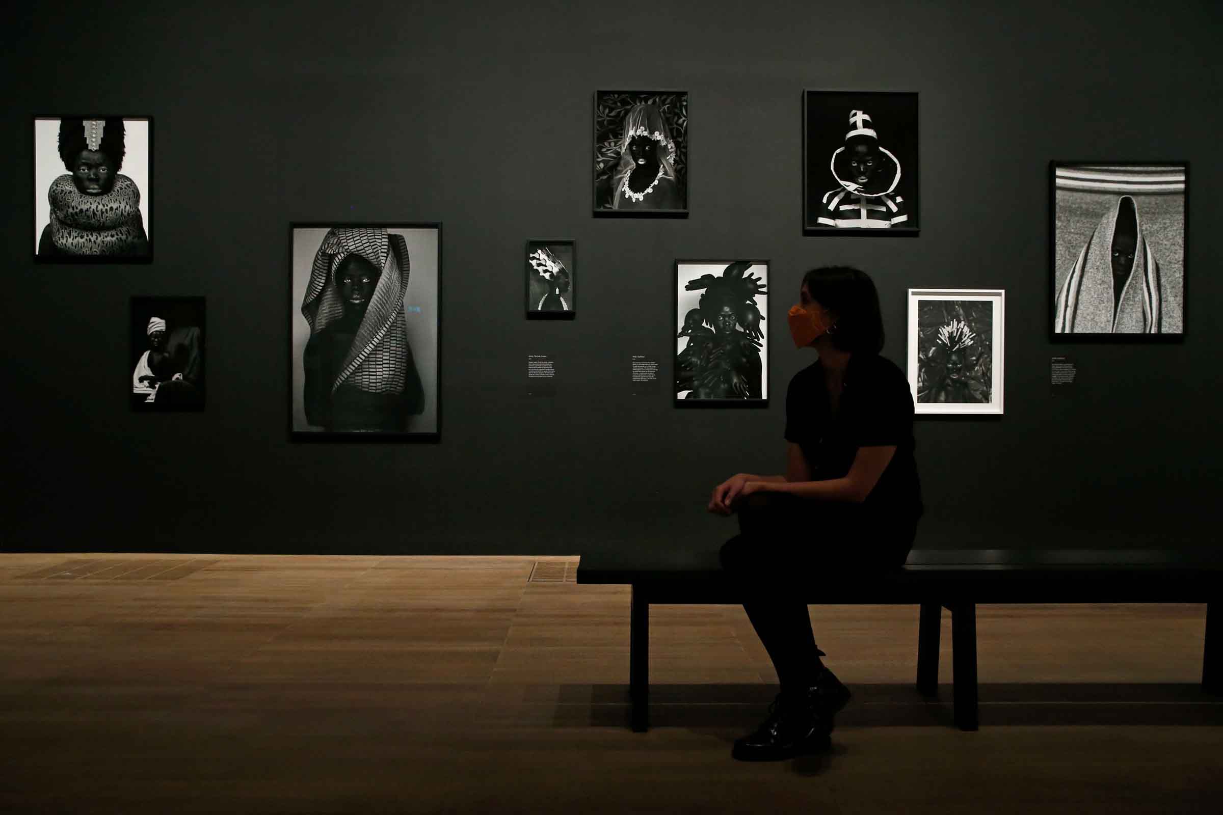 A Tate visitor poses in front of self portrait photographs from an on-going series entitled 'Somnyama Ngonyama' by South African visual activist Zanele Muholi in London on Nov. 3, 2020. (Holle Adams—AFP/Getty Images)