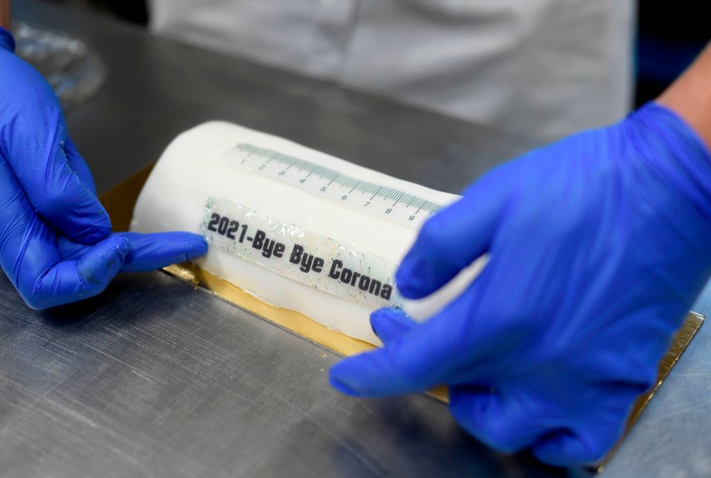 Bakery owner Tim Kortuem decorates a cake in the shape of a vaccination syringe and with the slogan '2021 Bye Bye Corona' at Schuerener Backparadies bakery in Dortmund, western Germany, during a partial lockdown to curb the spread of the ongoing novel coronavirus (Covid-19) pandemic. - Germany on January 5, 2021 prolonged and toughened its partial lockdown until January 31. (Photo by Ina FASSBENDER / AFP) (Photo by INA FASSBENDER/AFP via Getty Images) (AFP via Getty Images)