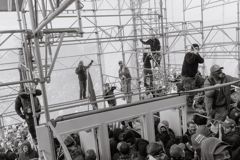 Pro-Trump rioters climb the scaffolding outside of the Capitol.