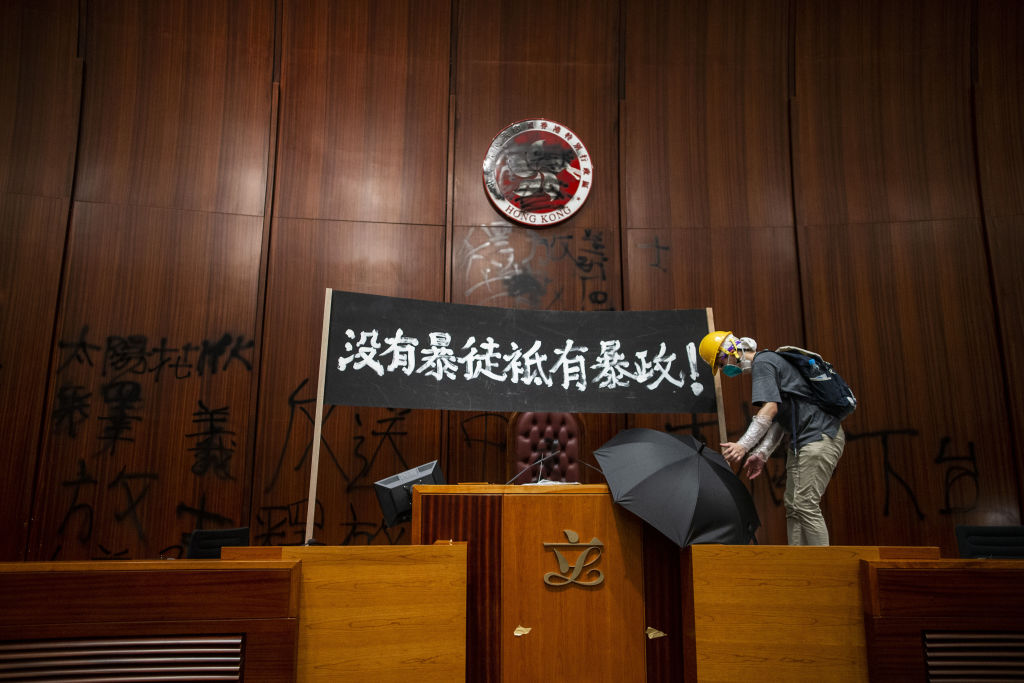 A demonstrator places an umbrella next to a banner reading 'There are no rioters, only tyranny' in Chinese, displayed inside the chamber of the Legislative Council in Hong Kong, China, on Monday, July 1, 2019. (Justin Chin/Bloomberg via Getty Images)