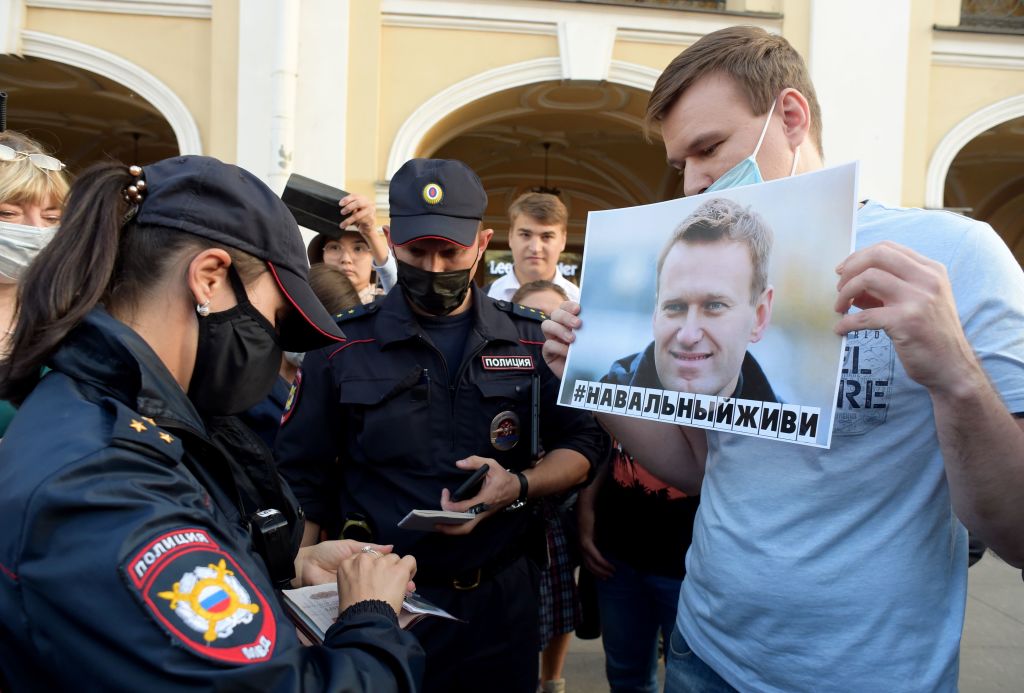 Police officers check documents of a man standing with a placard with an image of Alexei Navalny during a gathering to express support for the opposition leader after he was rushed to intensive care in Siberia suffering from a a suspected poisoning, in St. Petersburg on August 20, 2020. (Olga Maltseva—AFP/Getty Images)