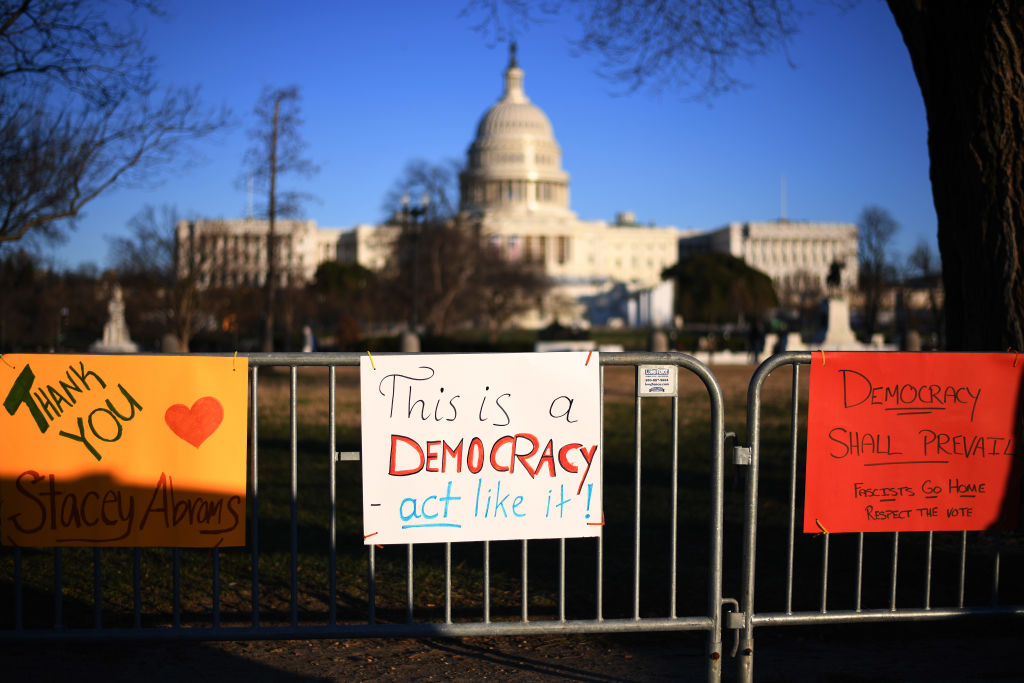 People place pro-democracy signs at a fence near the US Capitol building three days after it was stormed, invaded and vandalized by Trump rioters in Washington, Jan. 9, 2021. (Astrid Riecken—Washington Post/Getty Images)