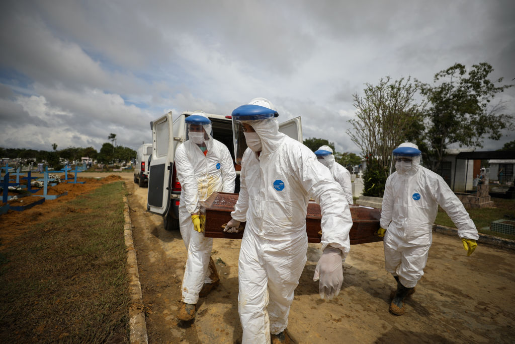Cemetery workers in protective suits carry the coffin of a person who died of Covid-19 at Nossa Senhora Aparecida Cemetery in Manaus on Jan.15 (Lucas Silva – Picture Alliance/Getty Images)