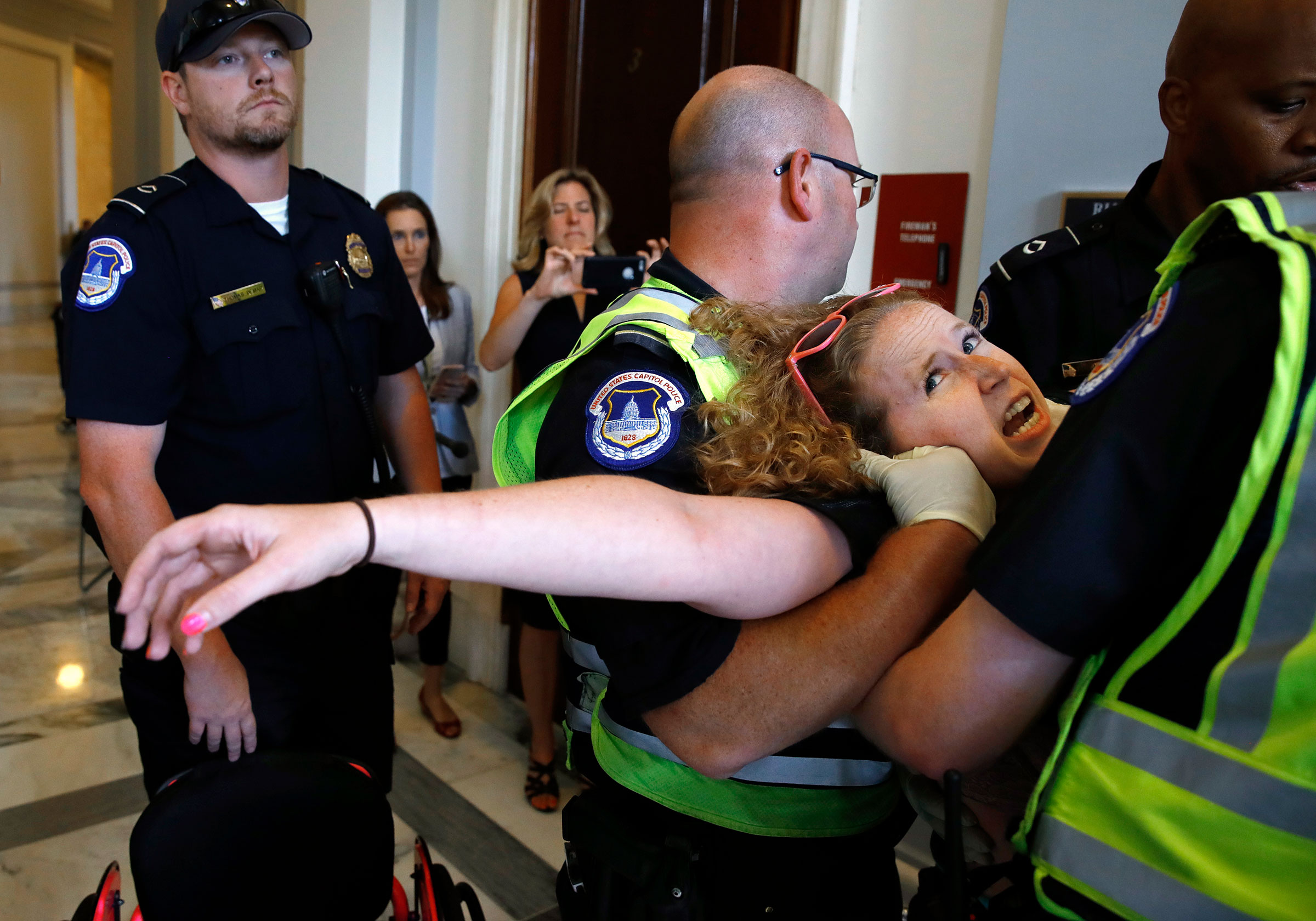 Stephanie Woodward, who has spina bifida and uses a wheelchair, is removed from a sit-in at Senate Majority Leader Mitch McConnell's office as she and other disability rights advocates protest proposed funding caps to Medicaid, on Capitol Hill on June 22, 2017.