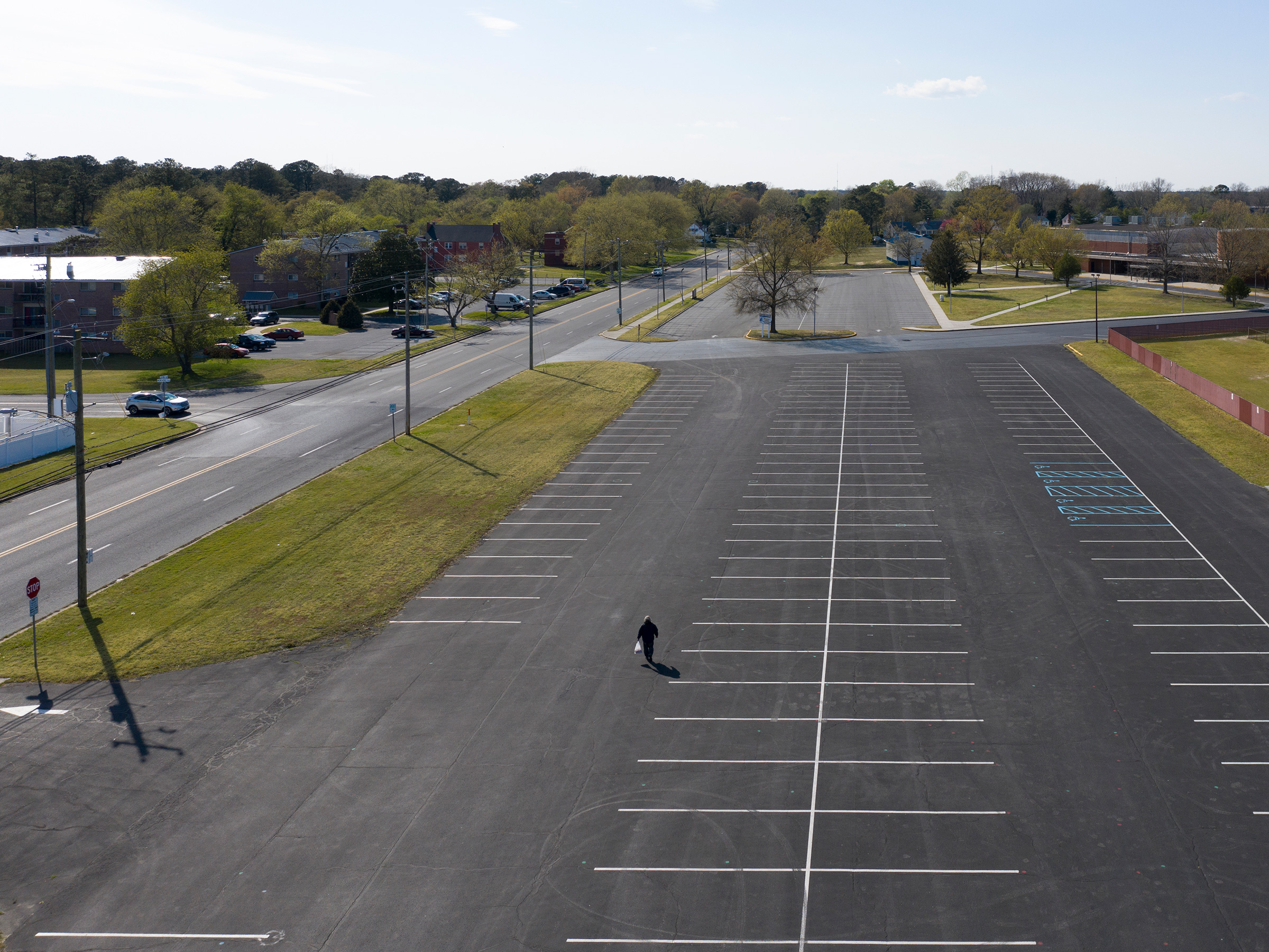<strong>Salisbury, Md., April 11, 2020.</strong> A man walks through the parking lot of the Wicomico County Stadium. "Before the pandemic, there was no reason to notice an empty parking lot. Now, besides the supermarket and Wal-Mart, every parking lot is empty." (Peter van Agtmael—Magnum Photos for TIME)