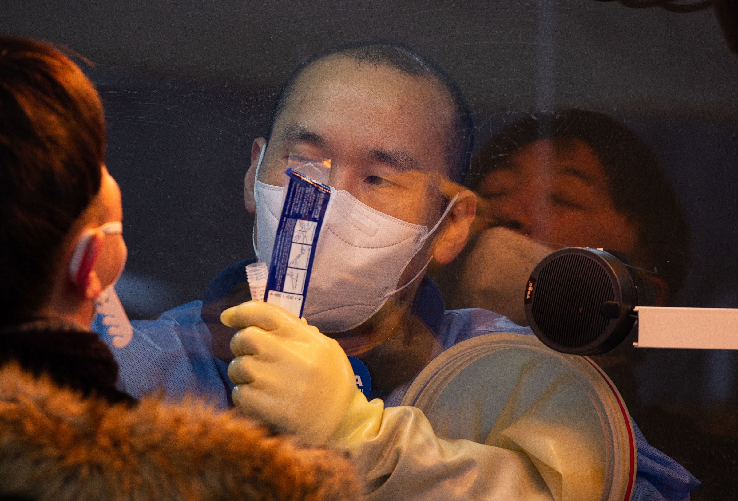 A health worker collects swabs from a citizen for COVID-19 testing at a makeshift clinic outside the Seoul city hall on Jan. 5