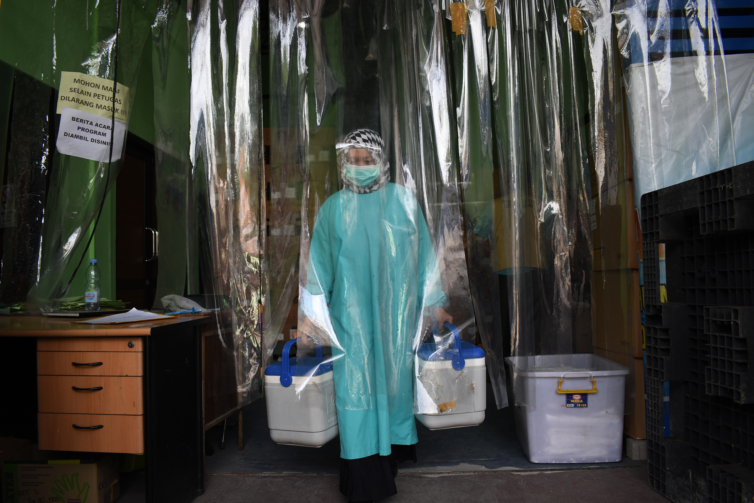 A health worker delivers containers of Covid-19 vaccines produced by China's Sinovac from a cold room in Bandung on Jan. 13 as the sprawling archipelago of nearly 270 million kicks off a mass innoculation drive in a bid to control soaring case rates