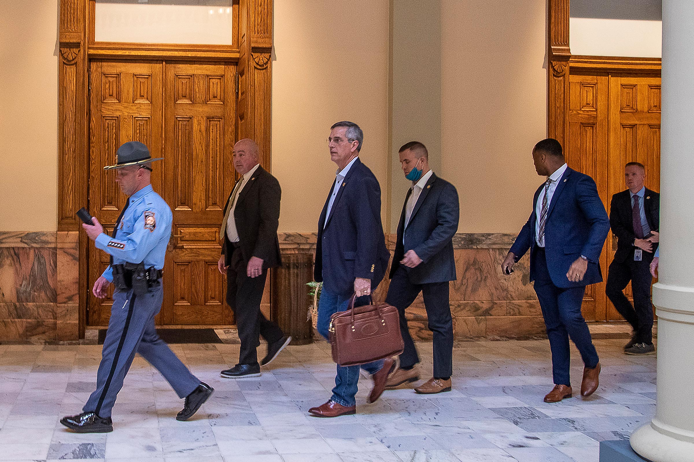 Lead by a Georgia State Trooper, Georgia Secretary of State Brad Raffensperger, center, exits the Georgia State Capitol building after hearing reports of threats, in Atlanta, Jan. 6, 2021. (Alyssa Pointer—Atlanta Journal-Constitution/AP)
