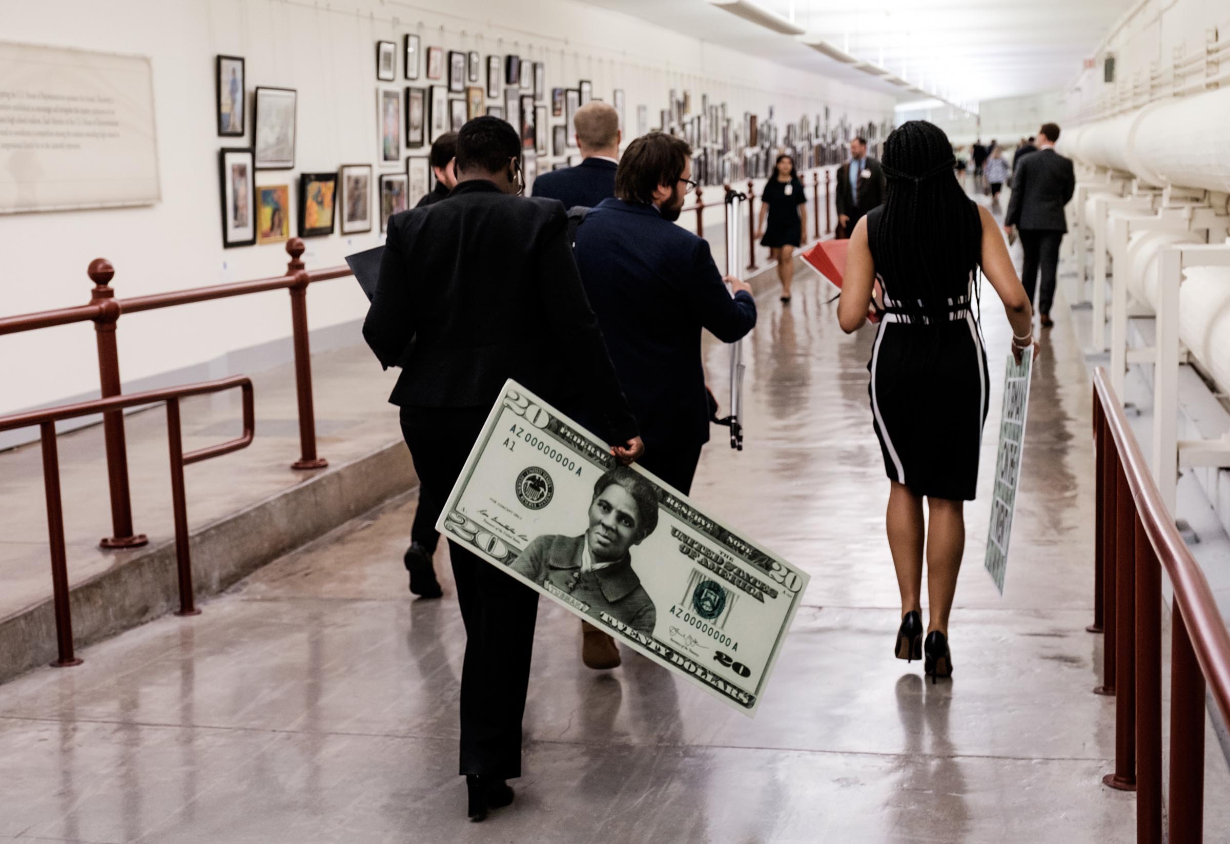 A congressional staffer departs holding a visual aide following a news conference regarding the redesigned $20 bill meant to honor Harriet Tubman.