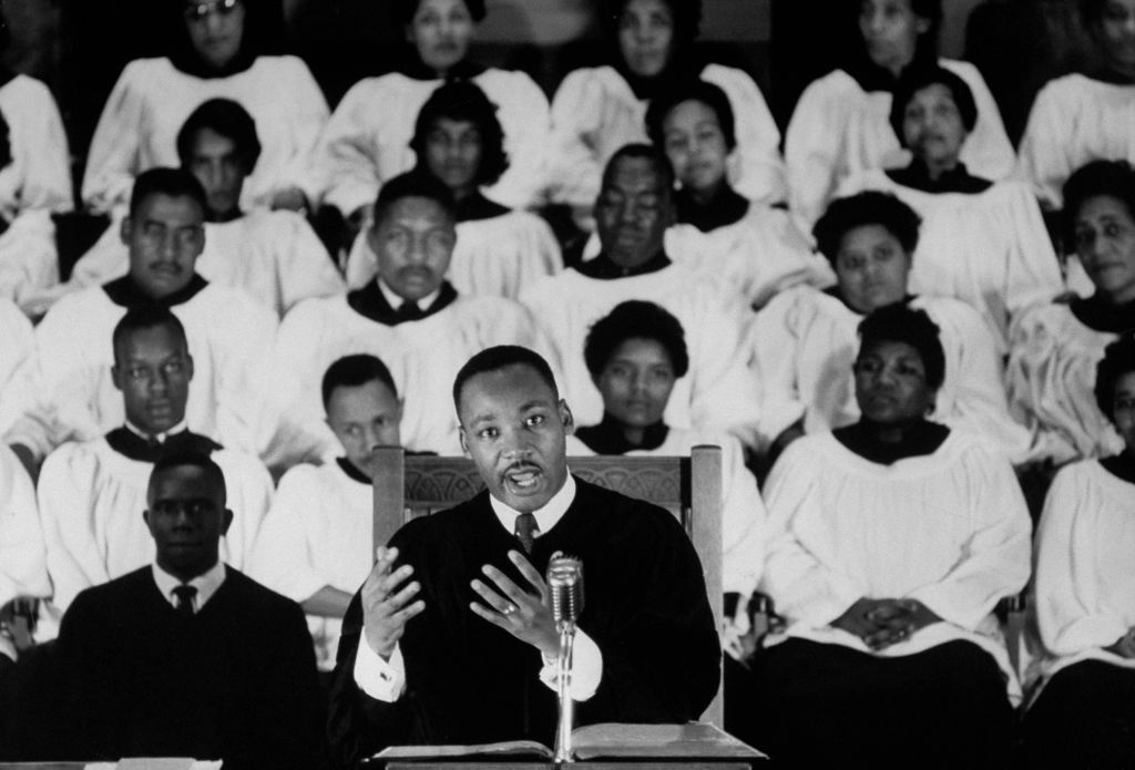 Civil Rights activist Rev. Dr. Martin Luther King Jr. standing at pulpit delivering a sermon as a white-robed choir listens in the background at Ebenezer Baptist Church in Atlanta, Georgia. (Donald Uhrbrock—The LIFE Images Collection/Getty Images)
