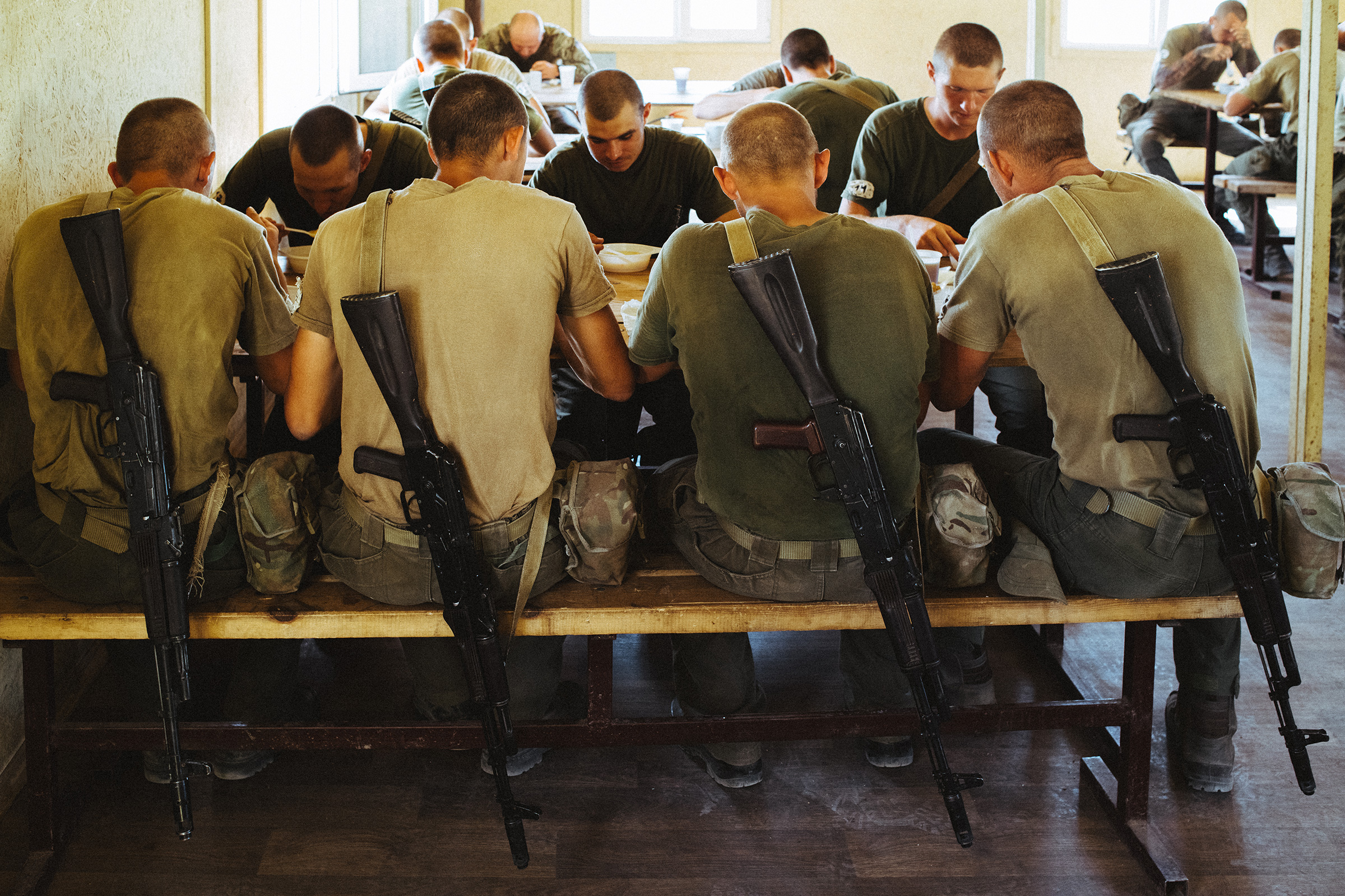 Weapons rest off the backs of recruits during a shared meal. At least since 2018, when the U.S. Congress explicitly barred any U.S. support for Azov, its fighters have been unable to train alongside troops from the U.S.-led NATO alliance. (Maxim Dondyuk for TIME)