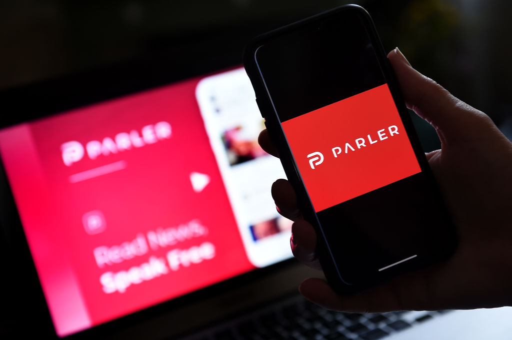 This illustration picture shows social media application logo from Parler displayed on a smartphone with its website in the background