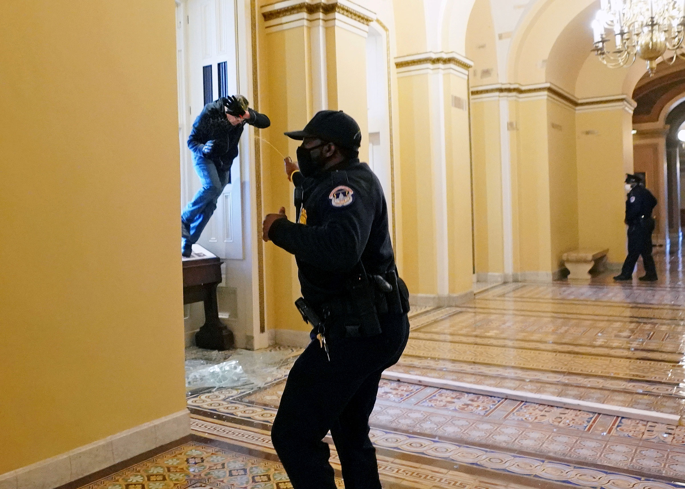 A Capitol police officer confronts a Trump supporter scrambling into the Capitol through a smashed window. (Kevin Dietsch—Pool/Reuters)
