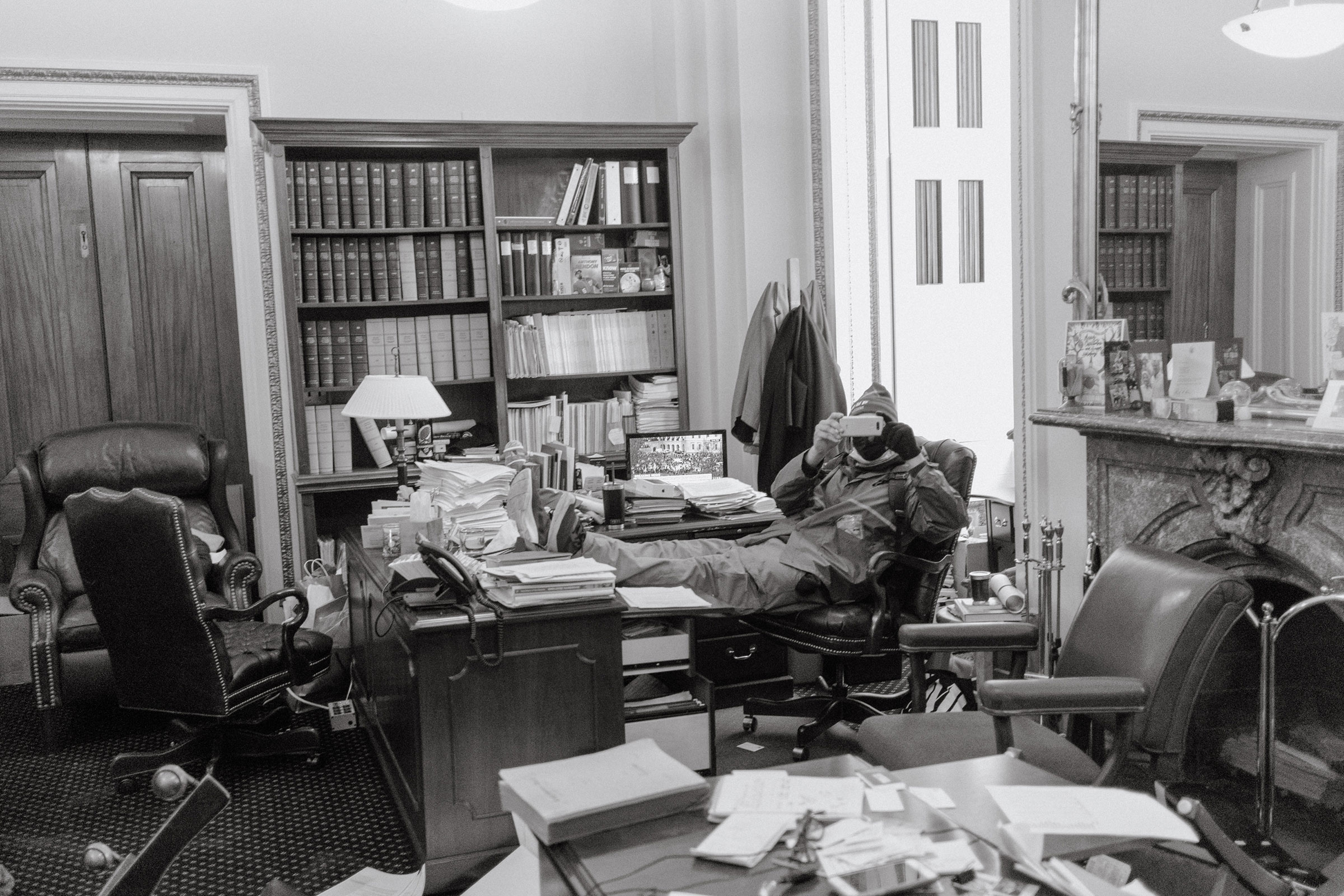 A pro-Trump rioter sits with their feet up on a desk inside an office in the Capitol. (Christopher Lee for TIME)
