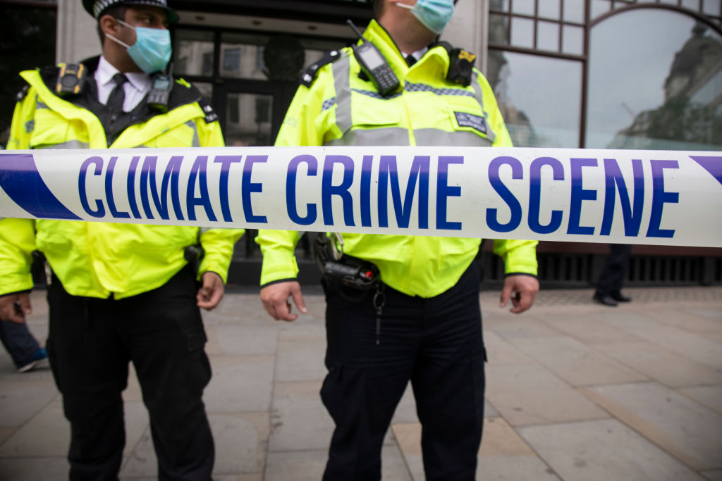 Police watch as Extinction Rebellion "crime scene investigators" in white suits and masks put up climate crime scene tape to investigate areas of ecocide in a performance outside the Brazilian Embassy on Sept. 7, 2020 in London, United Kingdom (Mike Kemp—In Pictures, via Getty Images)