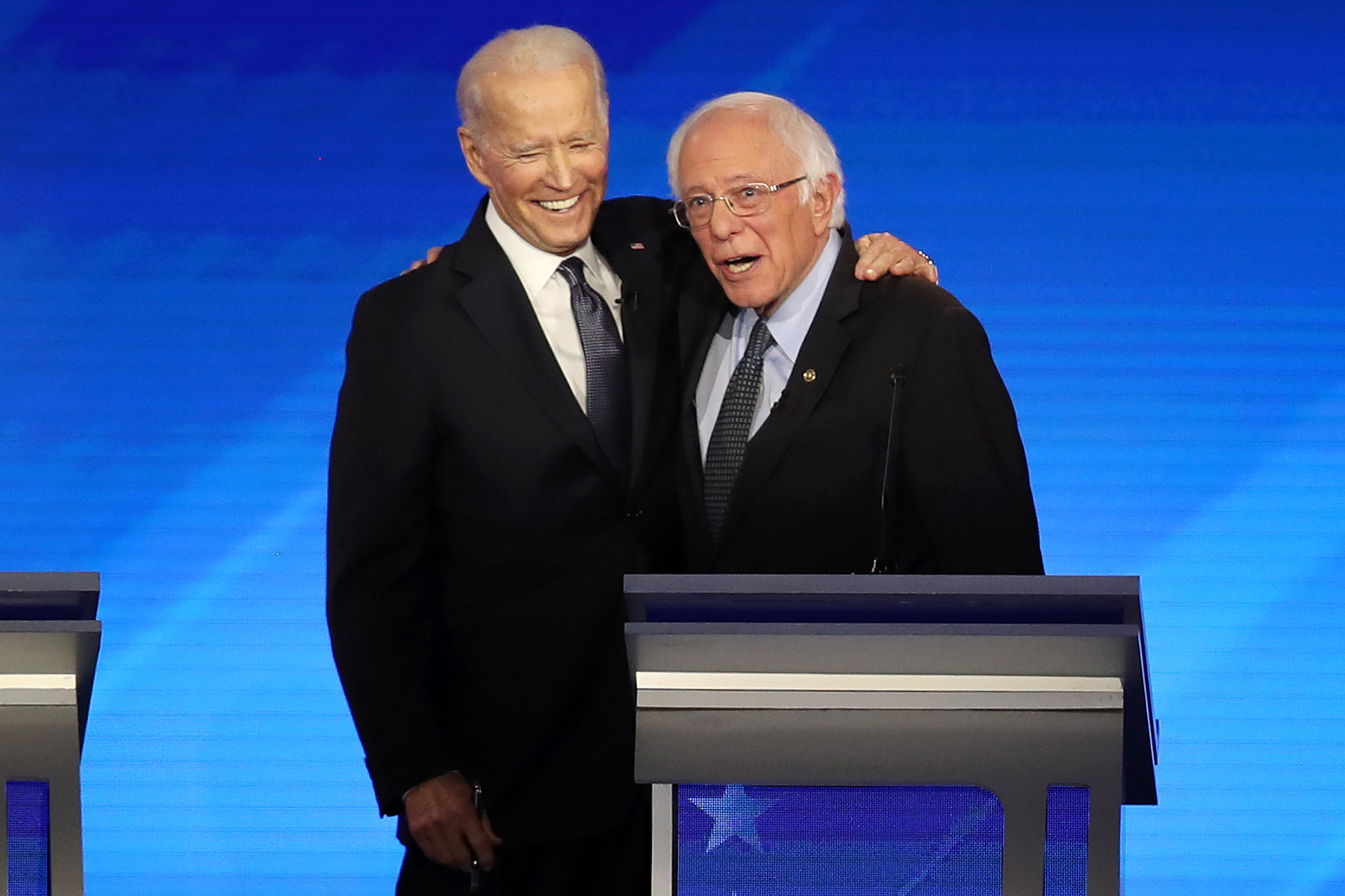 Then-presidential candidates Joe Biden and Sen. Bernie Sanders share a moment during the Democratic presidential primary debate in Manchester, N.H. on Feb. 7, 2020. (Joe Raedle—Getty Images)