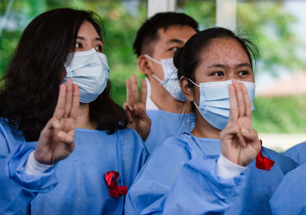 Medical staffs wearing facemasks and red ribbon tags raise