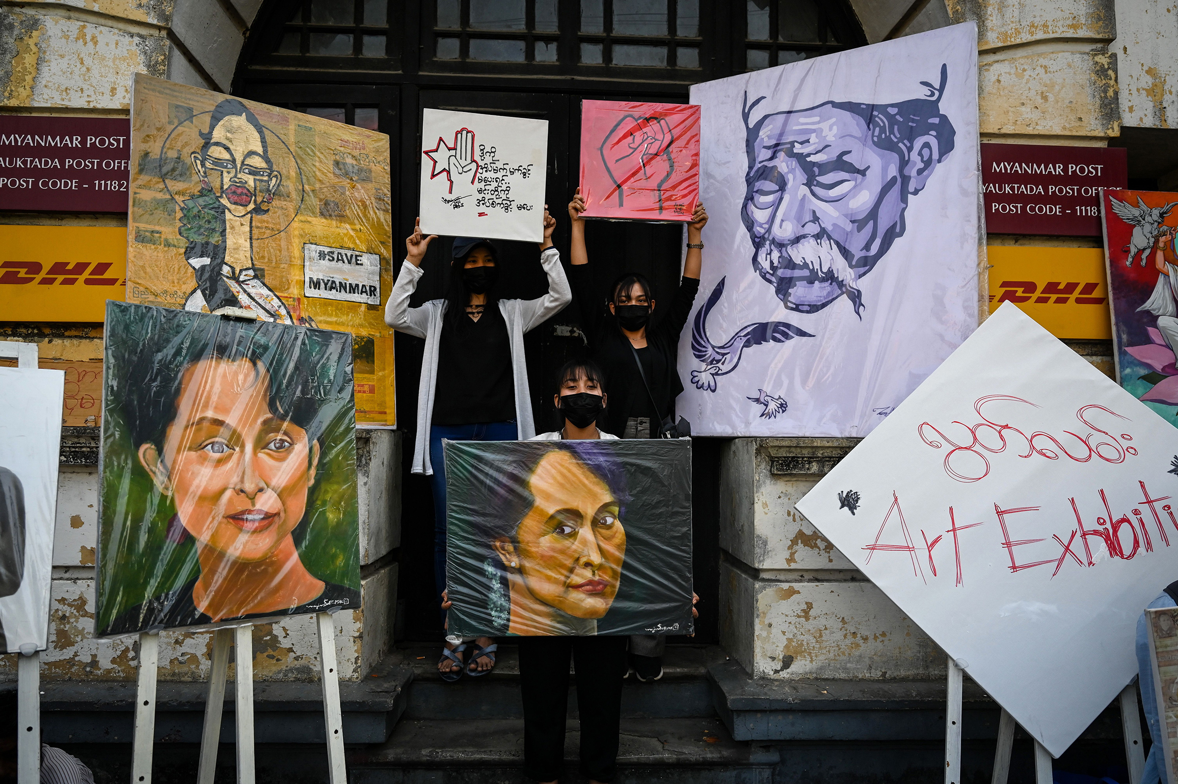 Protesters stand next to portraits of Aung San Suu Kyi and other artwork during a demonstration against the military coup in Yangon on Feb. 9