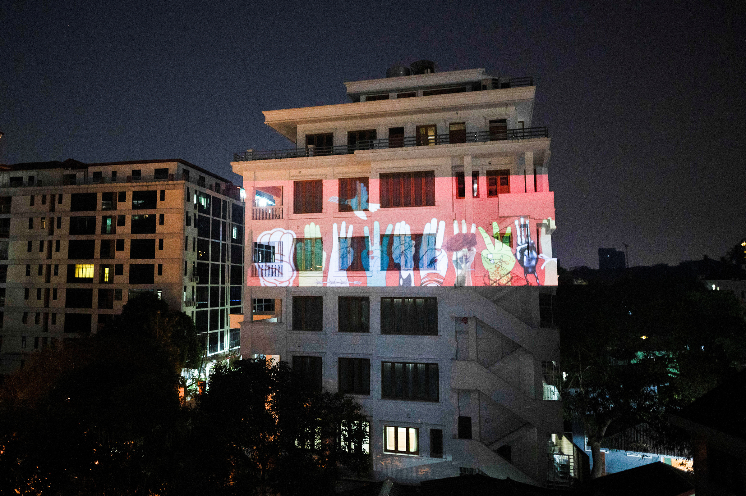 An image of three-finger salute is projected on a building during a night protest against the military coup and to demand the release of elected leader Aung San Suu Kyi, in Yangon, Myanmar, Feb. 9 (Reuters)