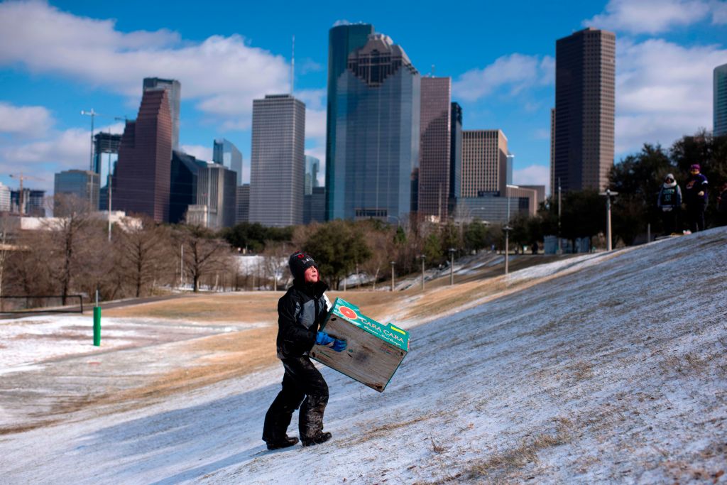 A boy walks up a snow covered hill after sledding down it in a box in Houston, Texas on Feb. 15, 2021. Much of the United States was in the icy grip of an "unprecedented" winter storm on Feb. 15, with as many as 5 million Americans losing power. (Mark Felix–AFP/Getty Images)