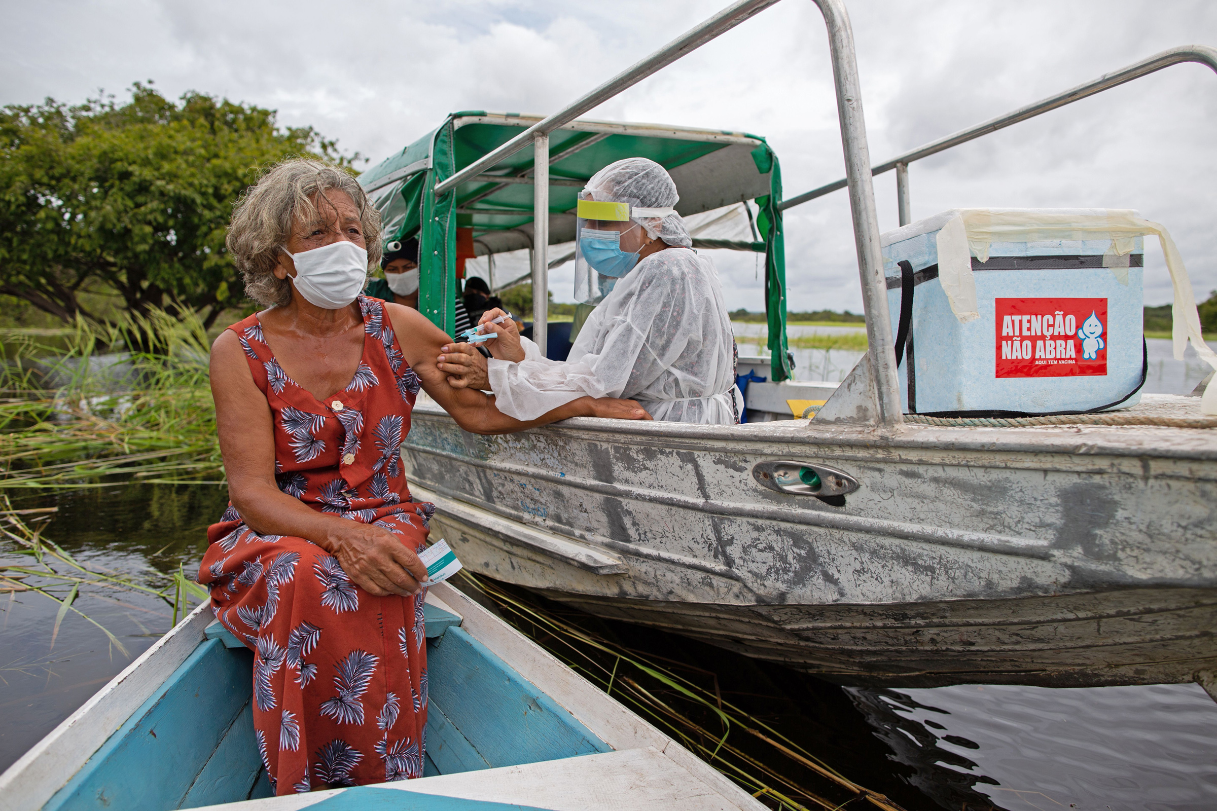 Olga D'arc Pimentel, 72, is vaccinated by a health worker with a dose of the Oxford-AstraZeneca COVID-19 vaccine on the banks of the Rio Negro near Manaus, Brazil, on Feb. 9, 2021. (Michael Dantas—AFP/Getty Images)