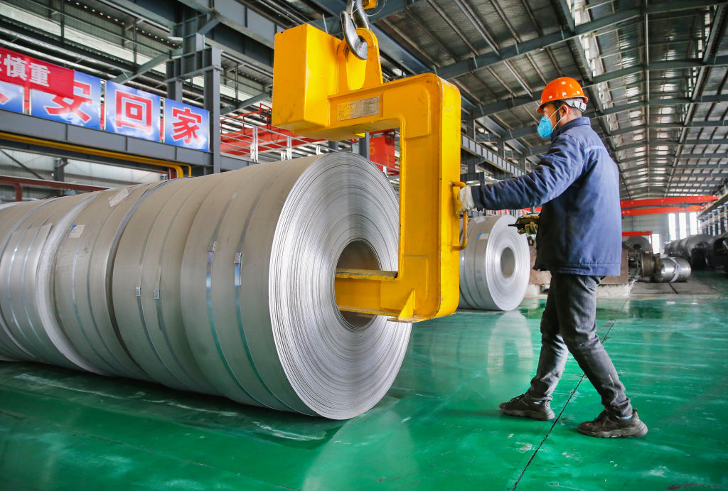 A worker transfers steel coils at a factory of Lianyungang Huale Alloy Group CO., LTD on February 24, 2021 in Lianyungang, Jiangsu Province of China. (Wang Jianmin/VCG via Getty Images)