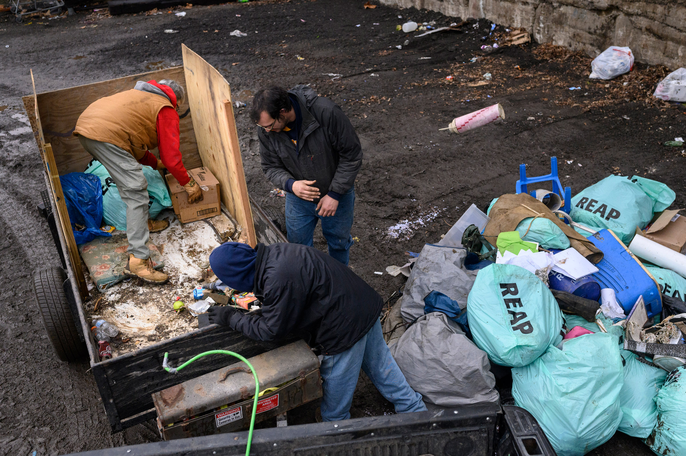 Paula Riethmiller and volunteers Gene and Michael dispose of trash found in encampments at the city dump in Wheeling on Dec. 21. Riethmiller helps lead Trash Talkers, an operation formed during the pandemic by the unhoused to solve trash accumulation in their tent encampments. Unhoused volunteers can earn gift cards and items such as phones through their volunteerism with the program.