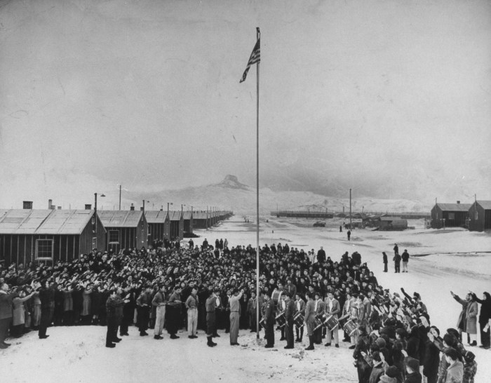 Nisei Japanese-Americans participating in a flag saluting ceremony at relocation center in forced internment during WWII, 1942