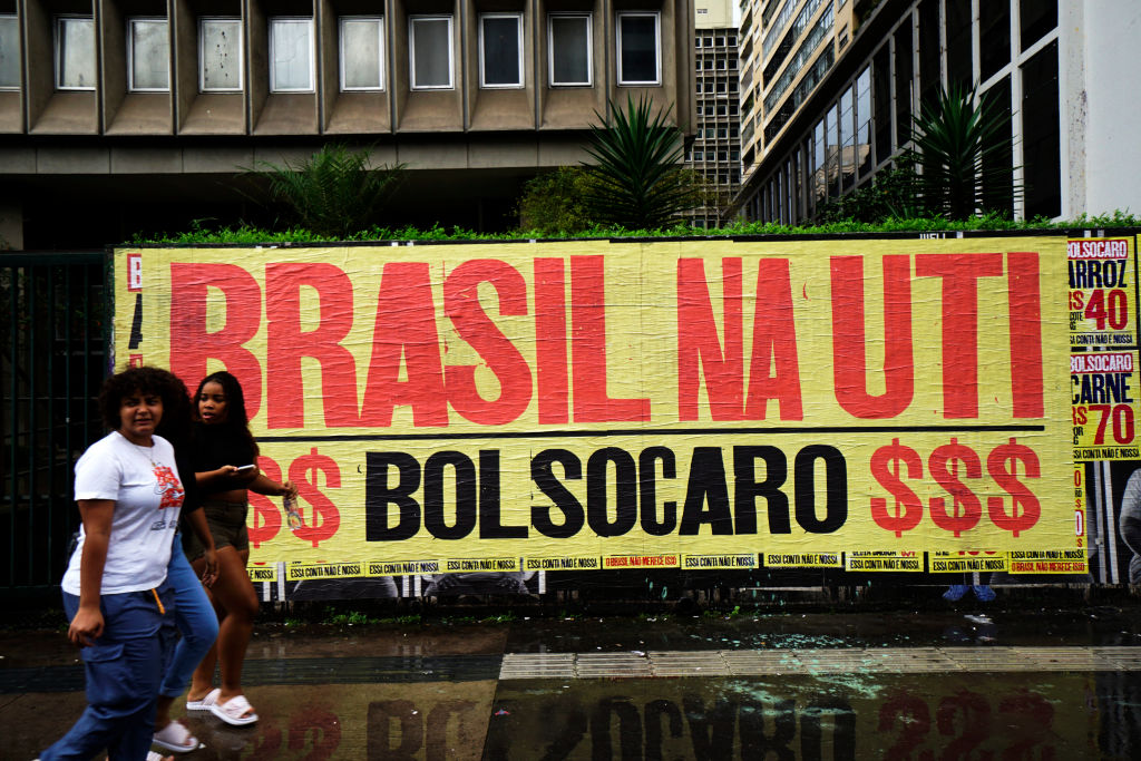 People walk in front of a banner that reads 'Brazil in the ICU, BolsoOverpriced' in reference to Brazilian president Jair Bolsonaro and the high prices of basic goods during the outbreak of COVID-19 in Sao Paulo, Brazil March 9, 2021. (Cris Faga –NurPhoto/Getty Images)
