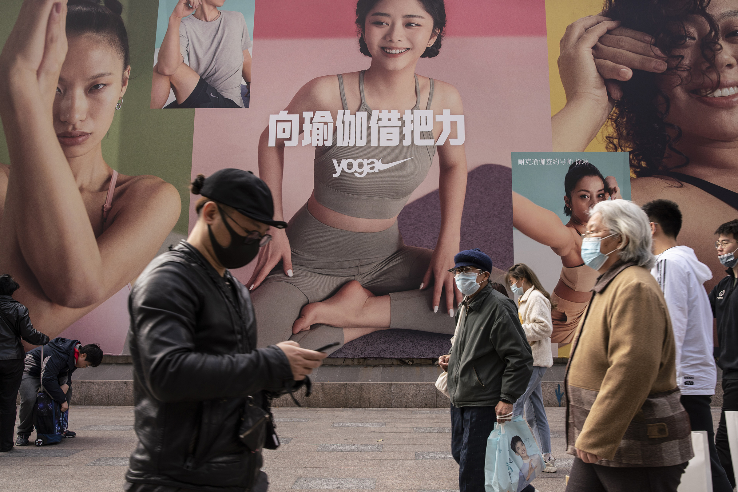 Pedestrians walk past a Nike yoga advertisement in Shanghai on March 26. China this week has pushed a campaign to boycott Western retailers after the U.S., U.K., Canada and the E.U. imposed sanctions over human-rights abuses against ethnic minority Uyghurs in Xinjiang.