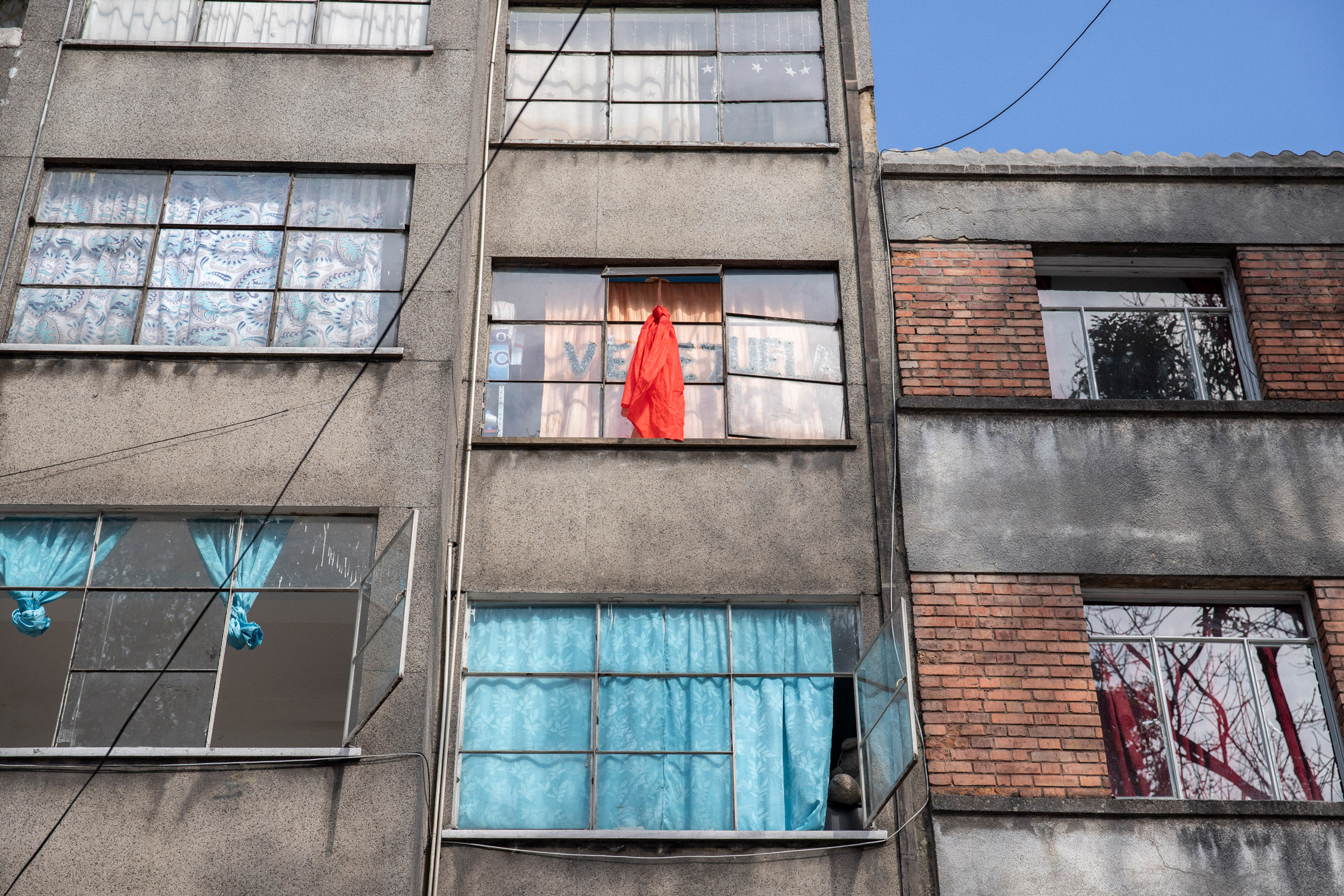 A building in Bogotá houses Venezuelan migrants. Occupants who are desperately in need of food place red fabric in their windows. (Fabiola Ferrero—National Geographic Society)