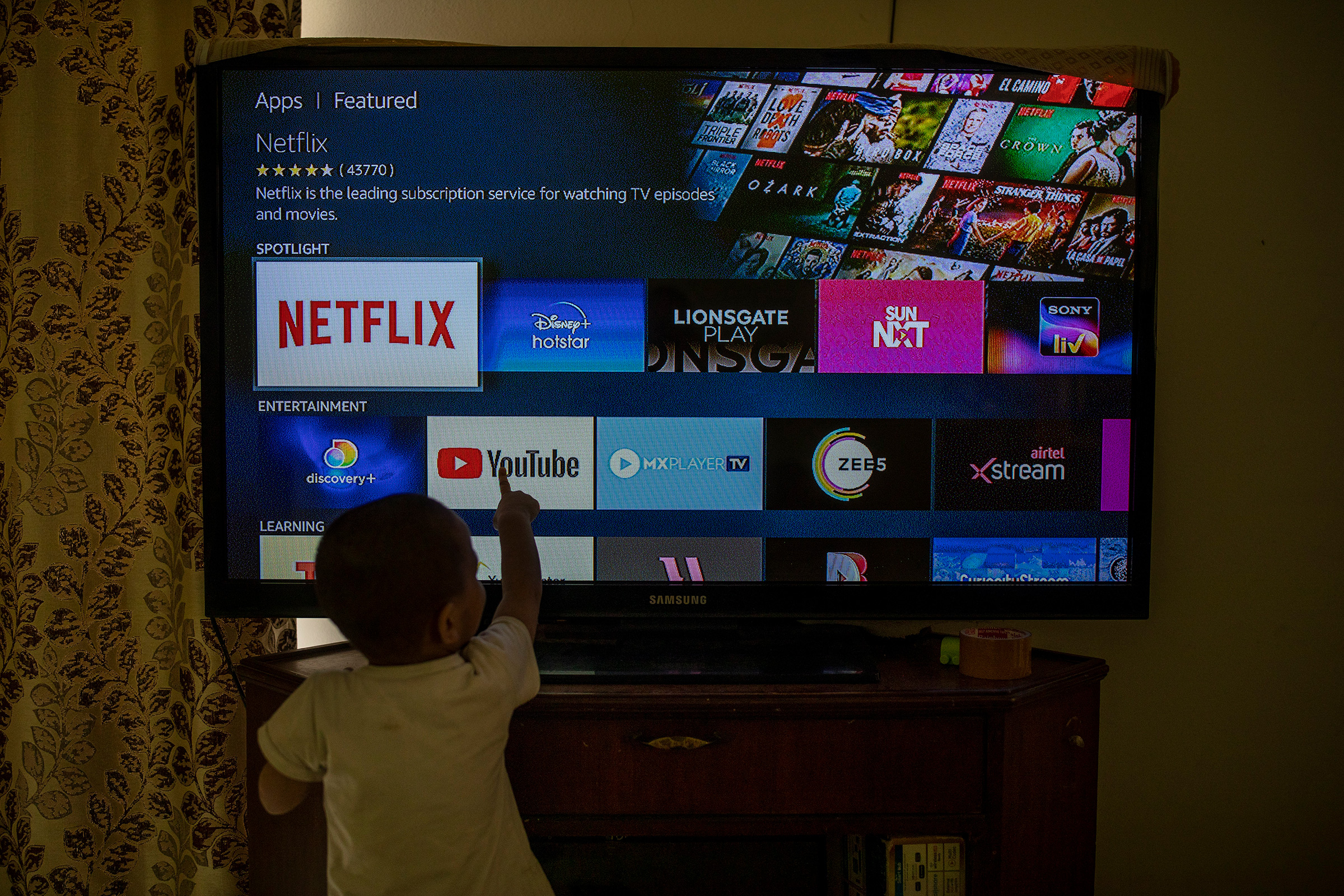 A child touches a TV screen displaying OTT streaming apps at his home in New Delhi, Feb. 25. India has rolled out new regulations for social media companies and digital streaming websites to make them more accountable for the online content shared on their platforms. (Altaf Qadri—AP)
