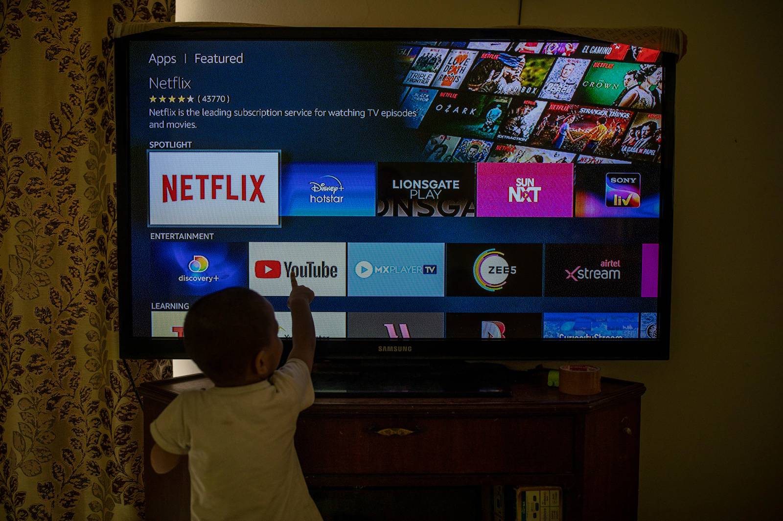 A child touches a TV screen displaying OTT streaming apps at his home in New Delhi, Feb. 25. India has rolled out new regulations for social media companies and digital streaming websites to make them more accountable for the online content shared on their platforms.