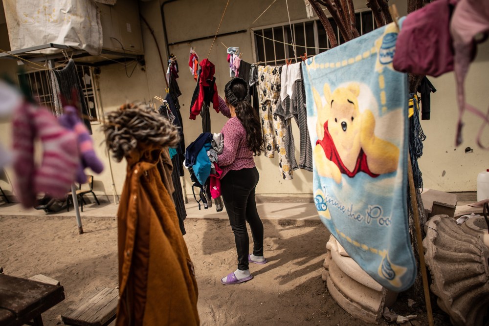 Carmen, a migrant fleeing violence in El Salvador, hangs her laundry to dry on a clothesline.