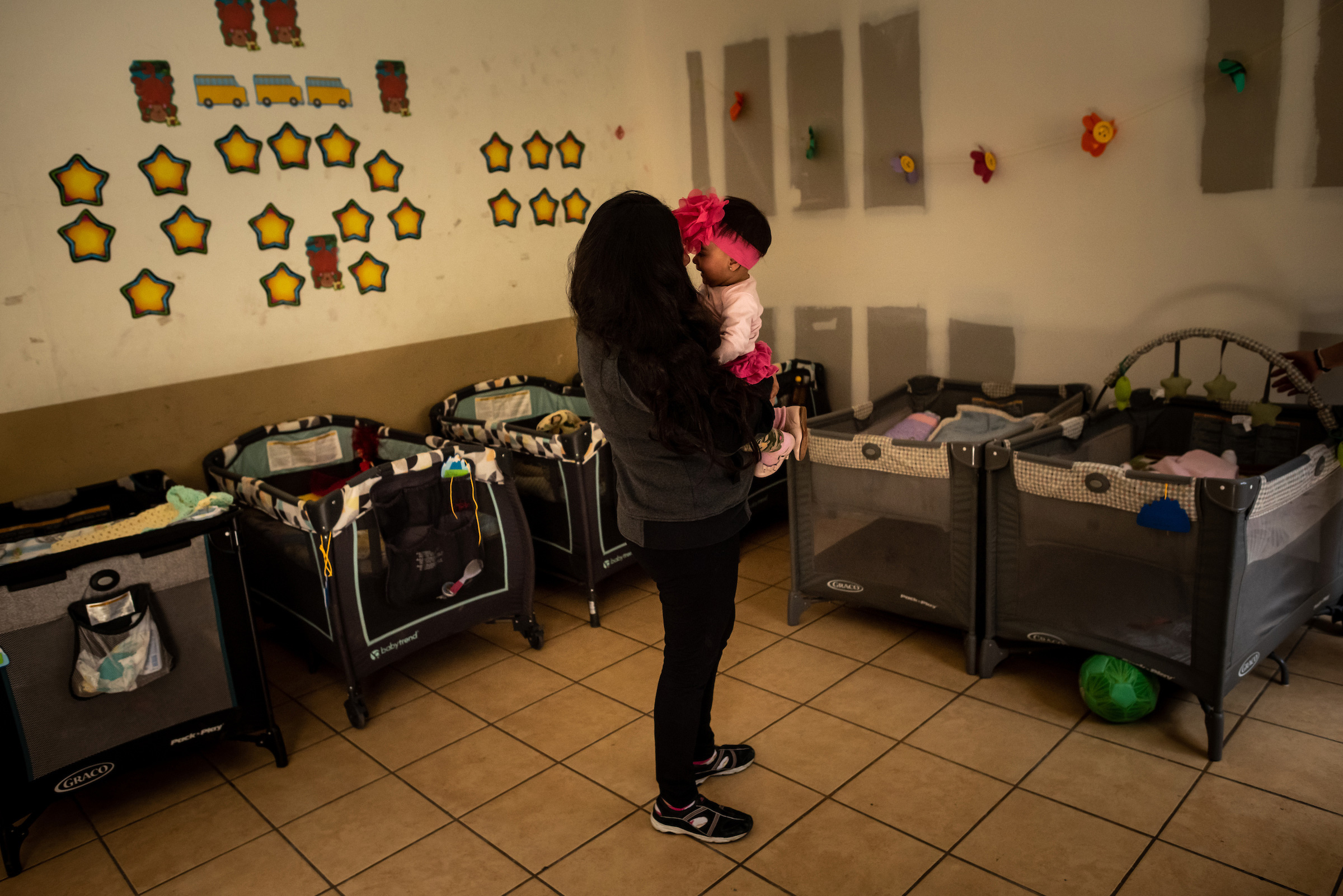 Xiomara plays with her baby in the nursery of the San Juan Apóstol migrant shelter. After fleeing gang violence in El Salvador, she arrived at the U.S.-Mexico border pregnant with her fourth child hoping to claim asylum. She gave birth in Ciudad Juárez, Mexico, with the help of volunteers. (Meridith Kohut for TIME)