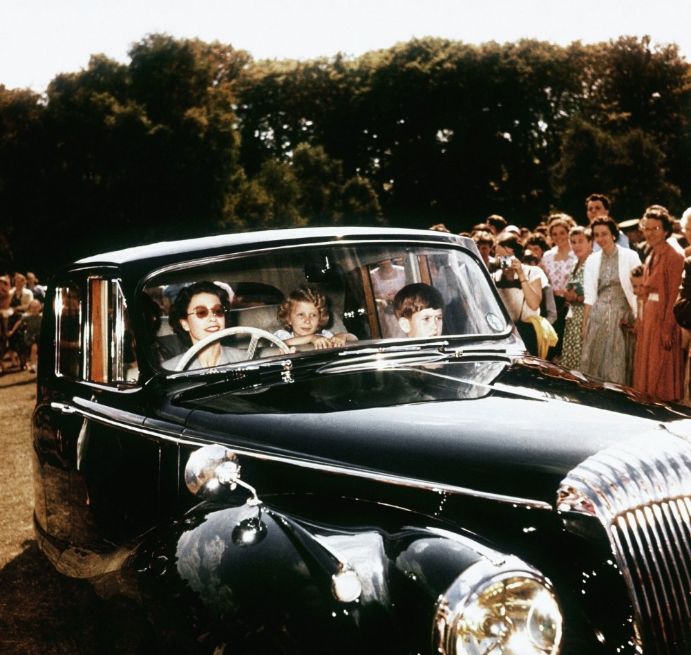 Queen Elizabeth II driving her children Prince Charles and Princess Anne at Windsor, 1957.